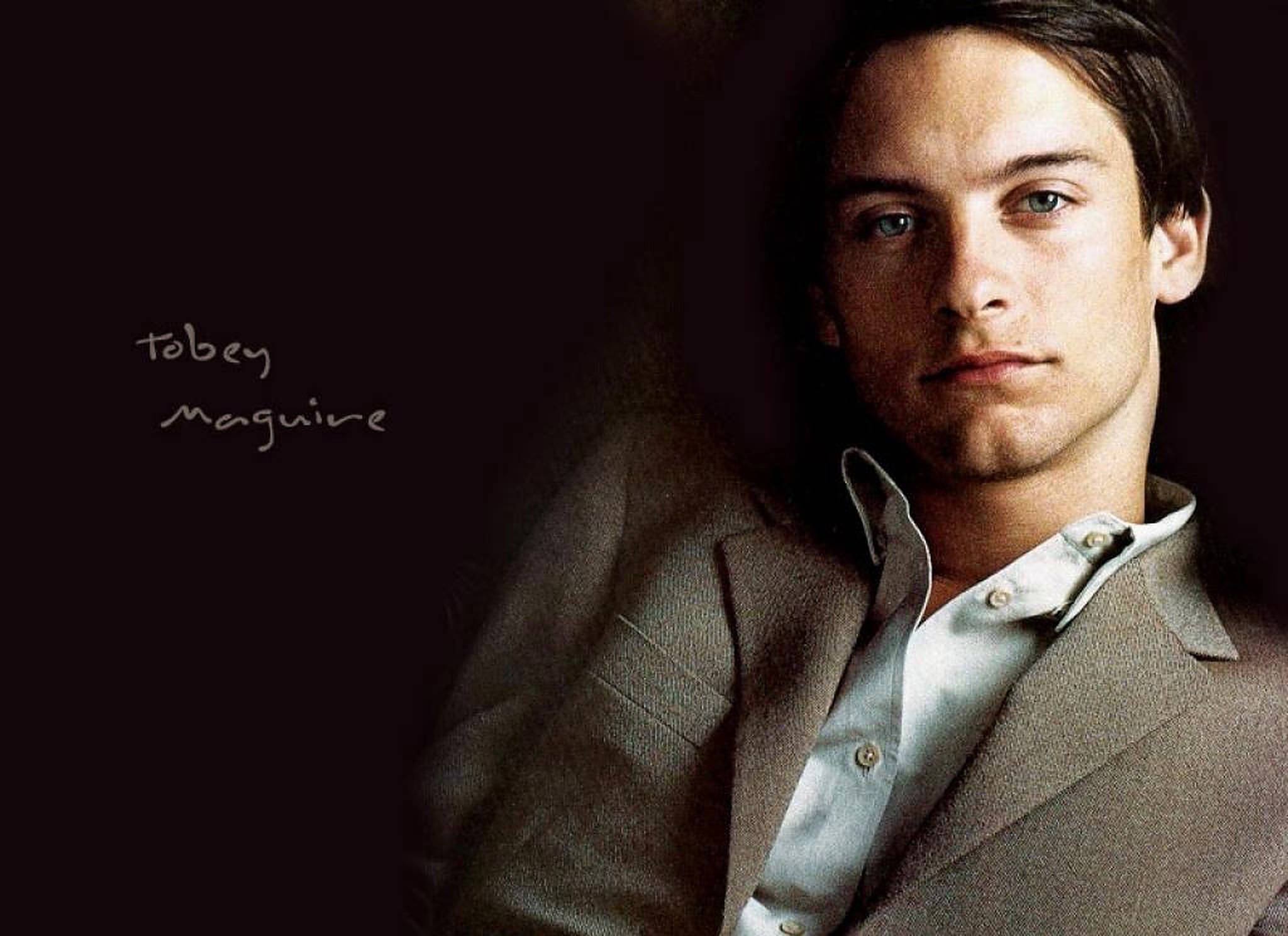 Tobey Maguire 桌布 壁紙 — 杜比·麥奎爾在昏暗的肖像照中凝視著，身穿質感棕色西裝外套，內搭白襯衫。