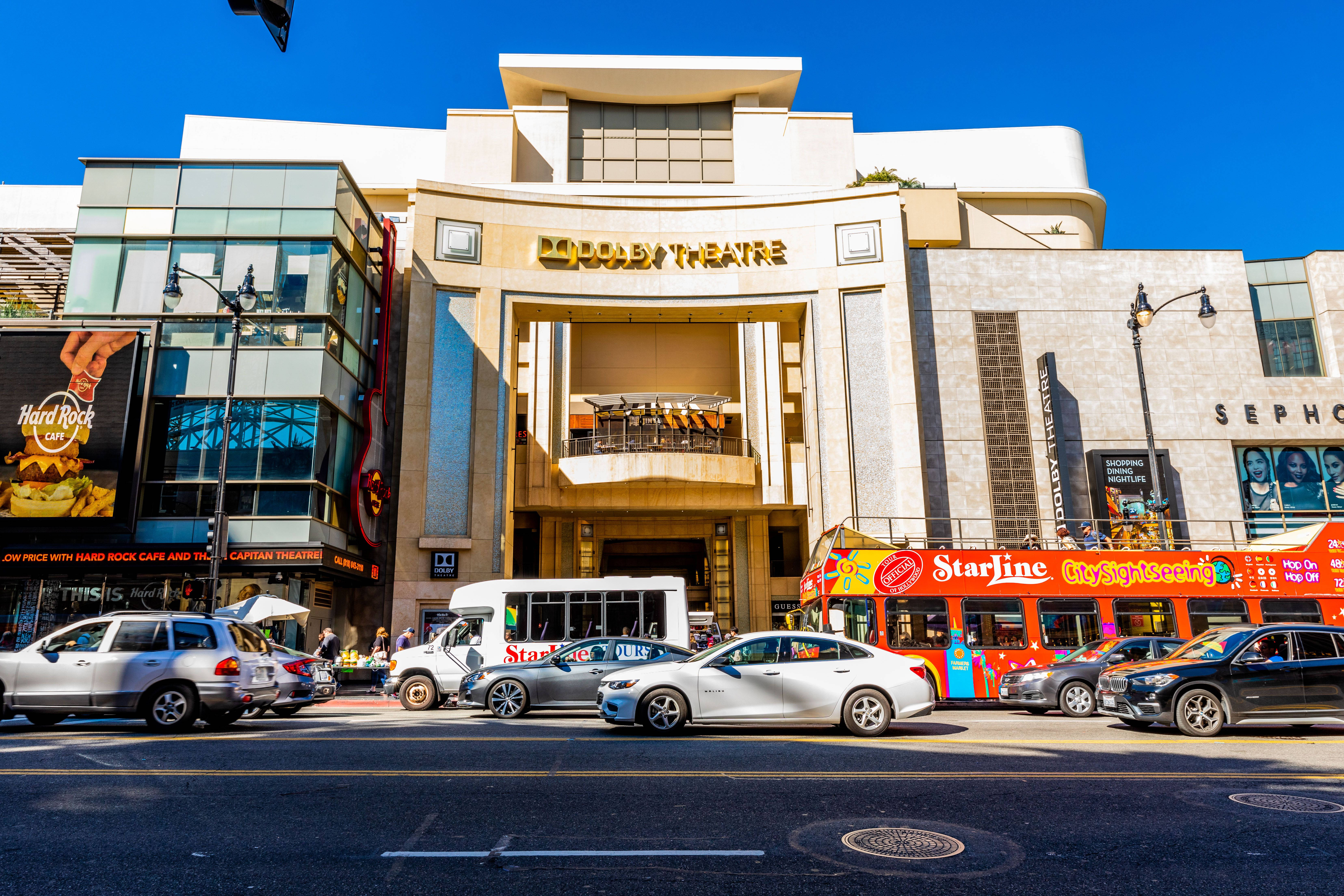 hollywood street 桌布 壁紙 — 杜比劇院陽光明媚的一天，交通繁忙，附近停著一輛紅色雙層觀光巴士。