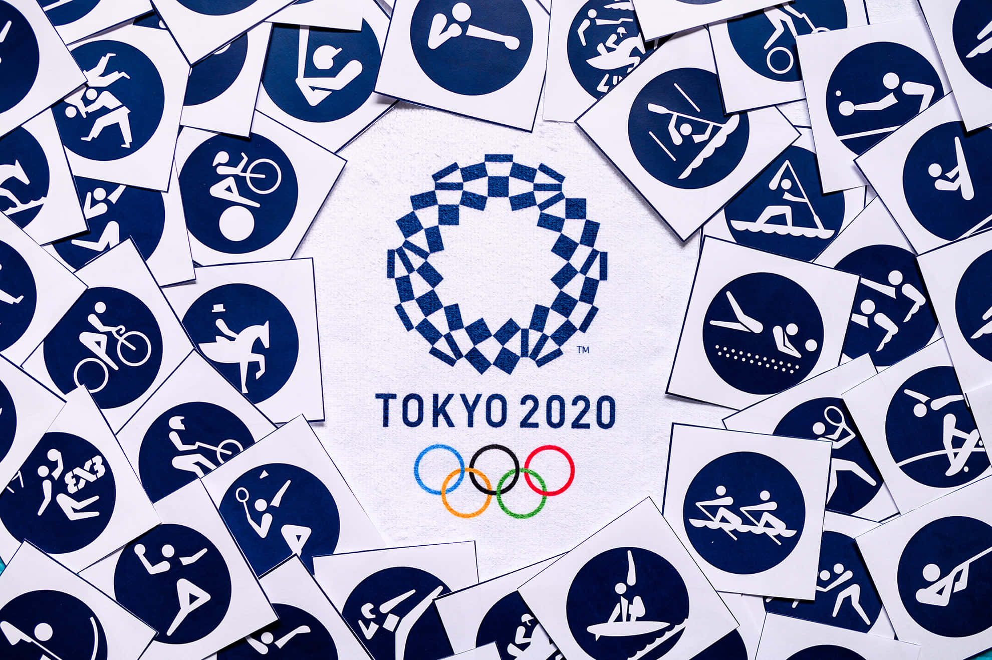 Olympics 桌布 壁紙 — 東京2020奧運標誌被散落的運動象形圖環繞在白色表面上。