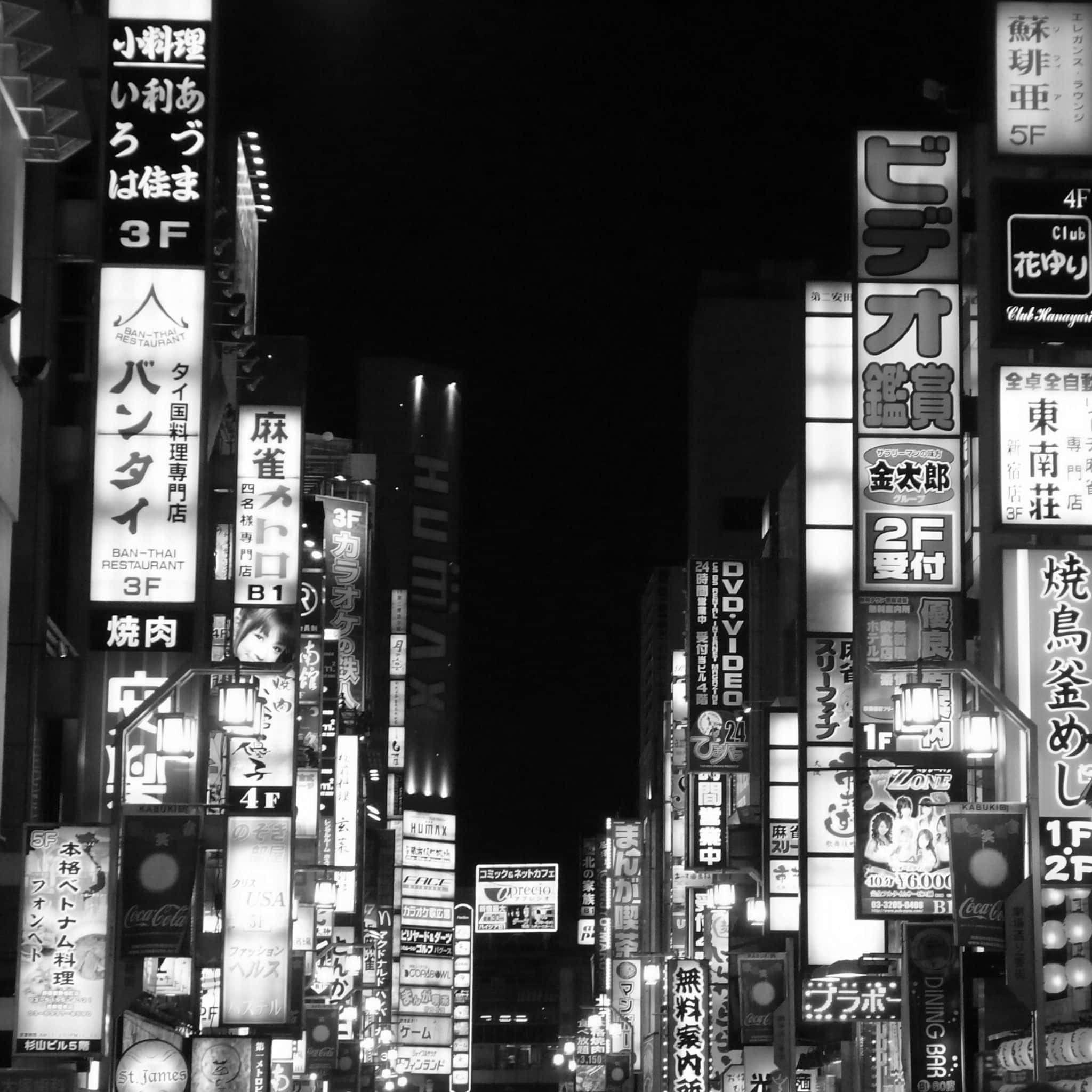 日本黑白 桌布 壁紙 — 東京一條密集街道的醒目黑白夜景，街道上有高聳的日文發光招牌。
