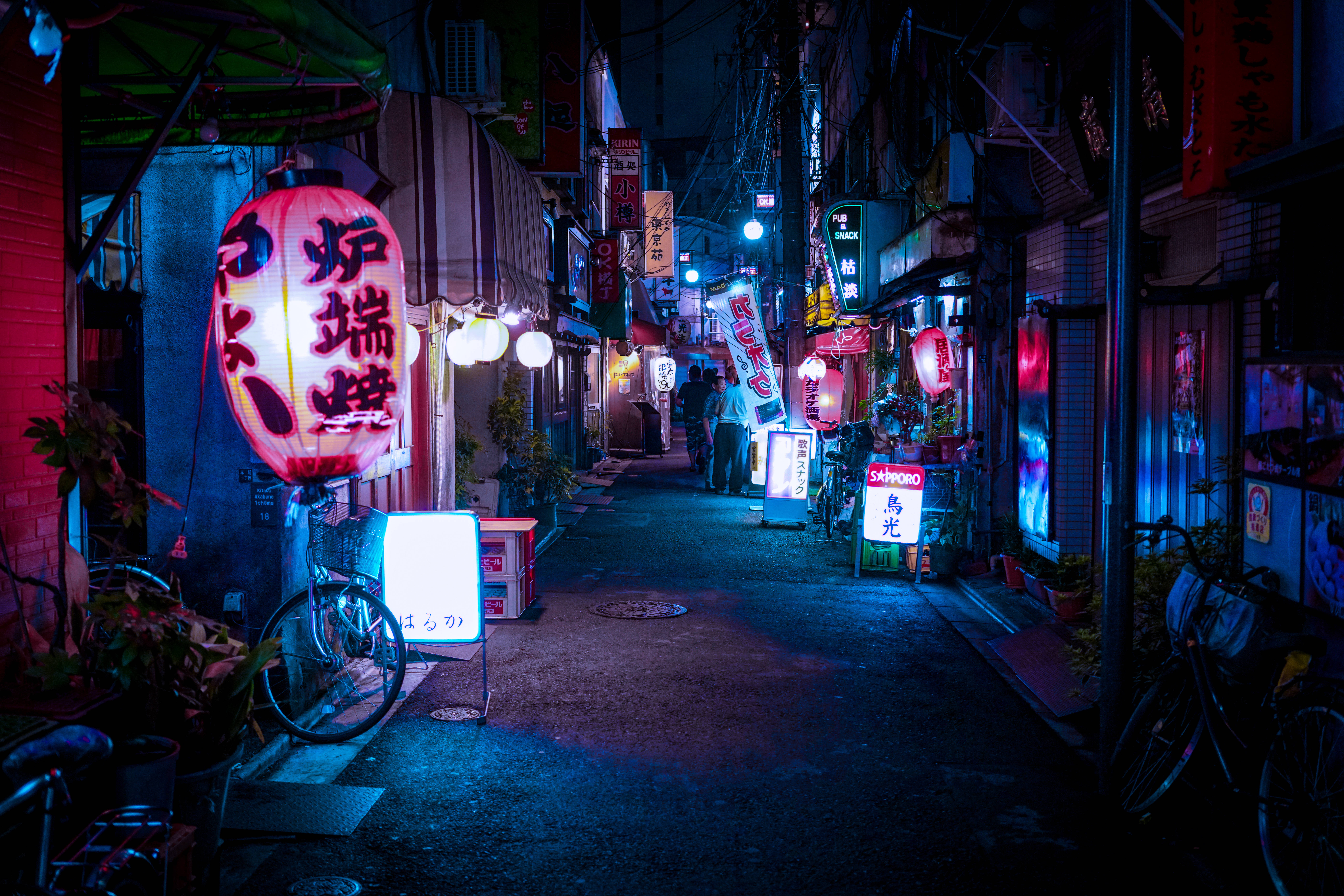 動漫 桌布 壁紙 — 東京一條狹窄的小巷，夜晚被發光的紅藍霓虹燈和燈籠照亮，在潮濕的路面上投射出色彩繽紛的倒影。