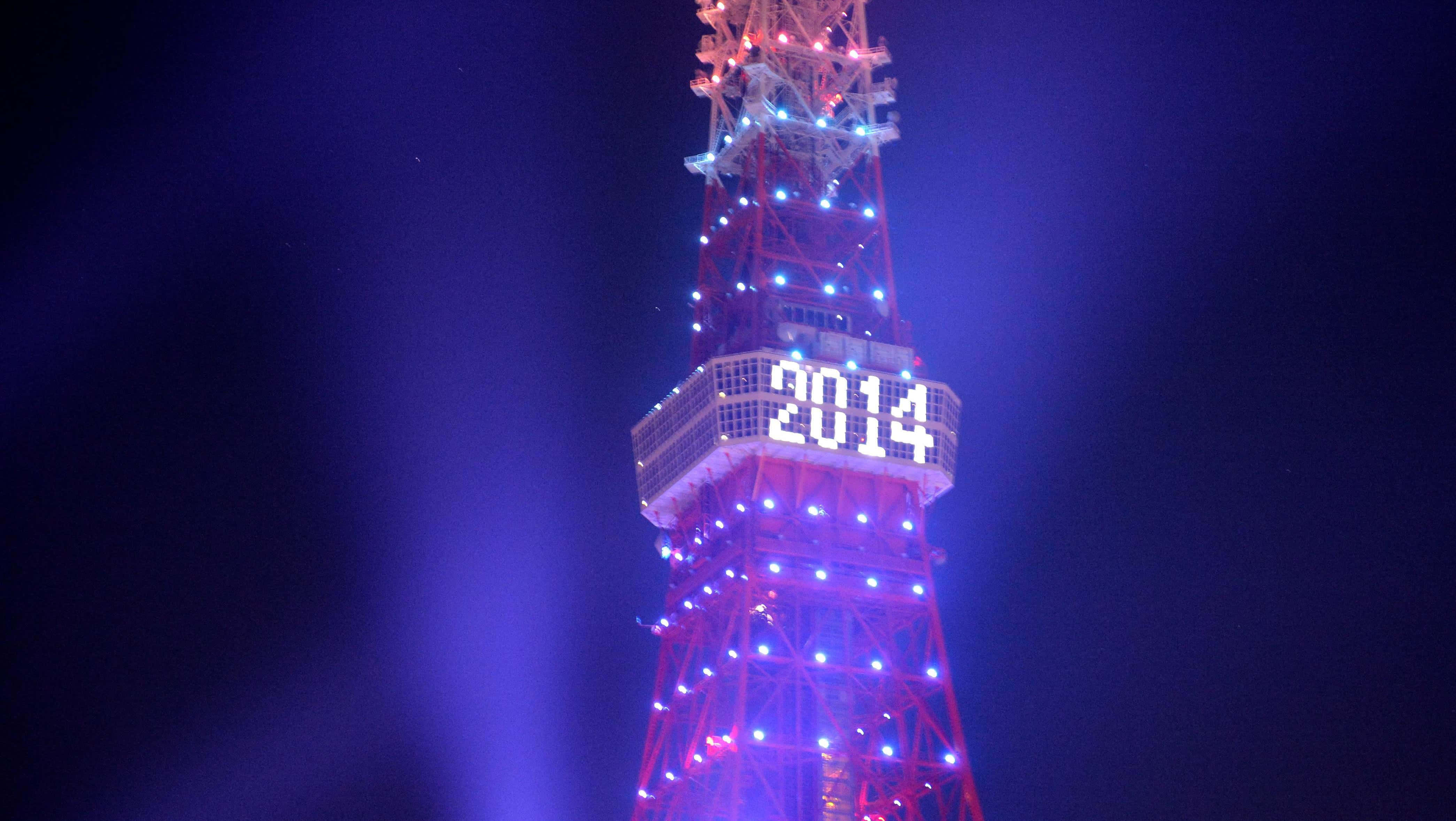 城市 桌布 壁紙 — 東京塔在夜間被發光的藍色和紅色燈光照亮，中間部分有一個明亮的2014數字顯示屏。
