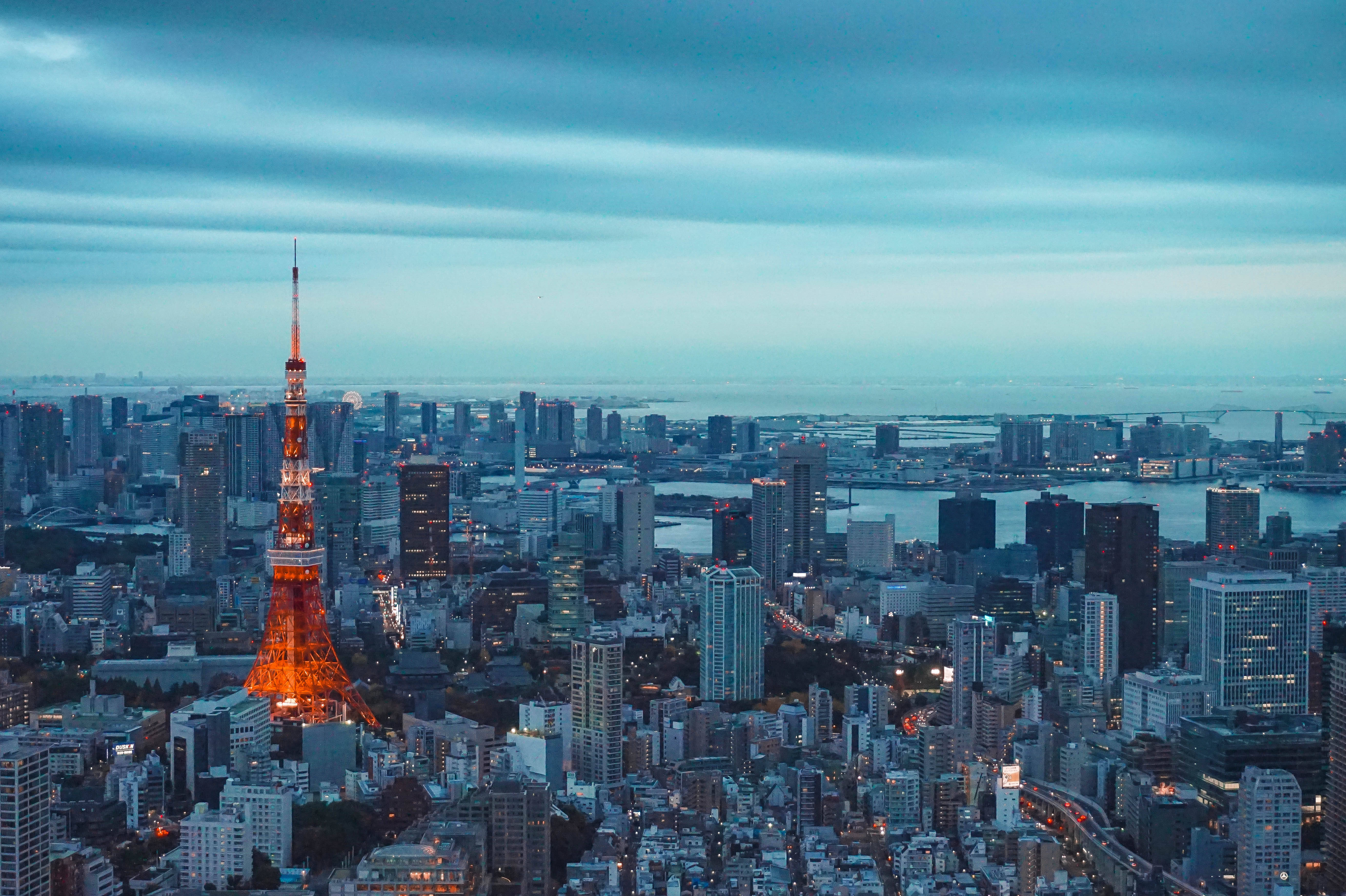 日本 桌布 壁紙 — 東京塔在暮色藍天下溫暖發光，城市燈光在都市擴展區中閃爍。