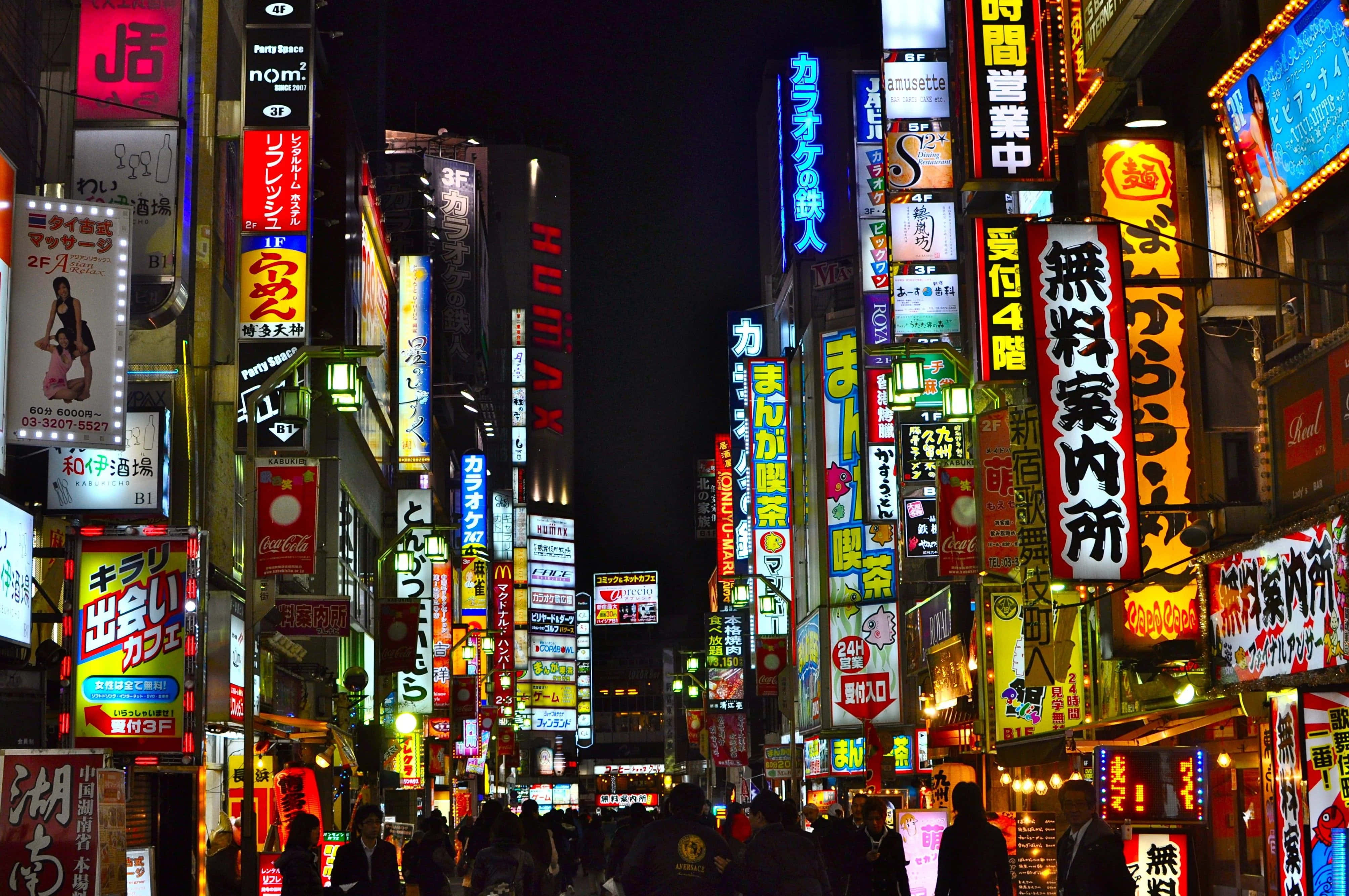 neon sign 桌布 壁紙 — 東京夜晚一條耀眼的霓虹燈城市街道，高聳的招牌和下方的人群。