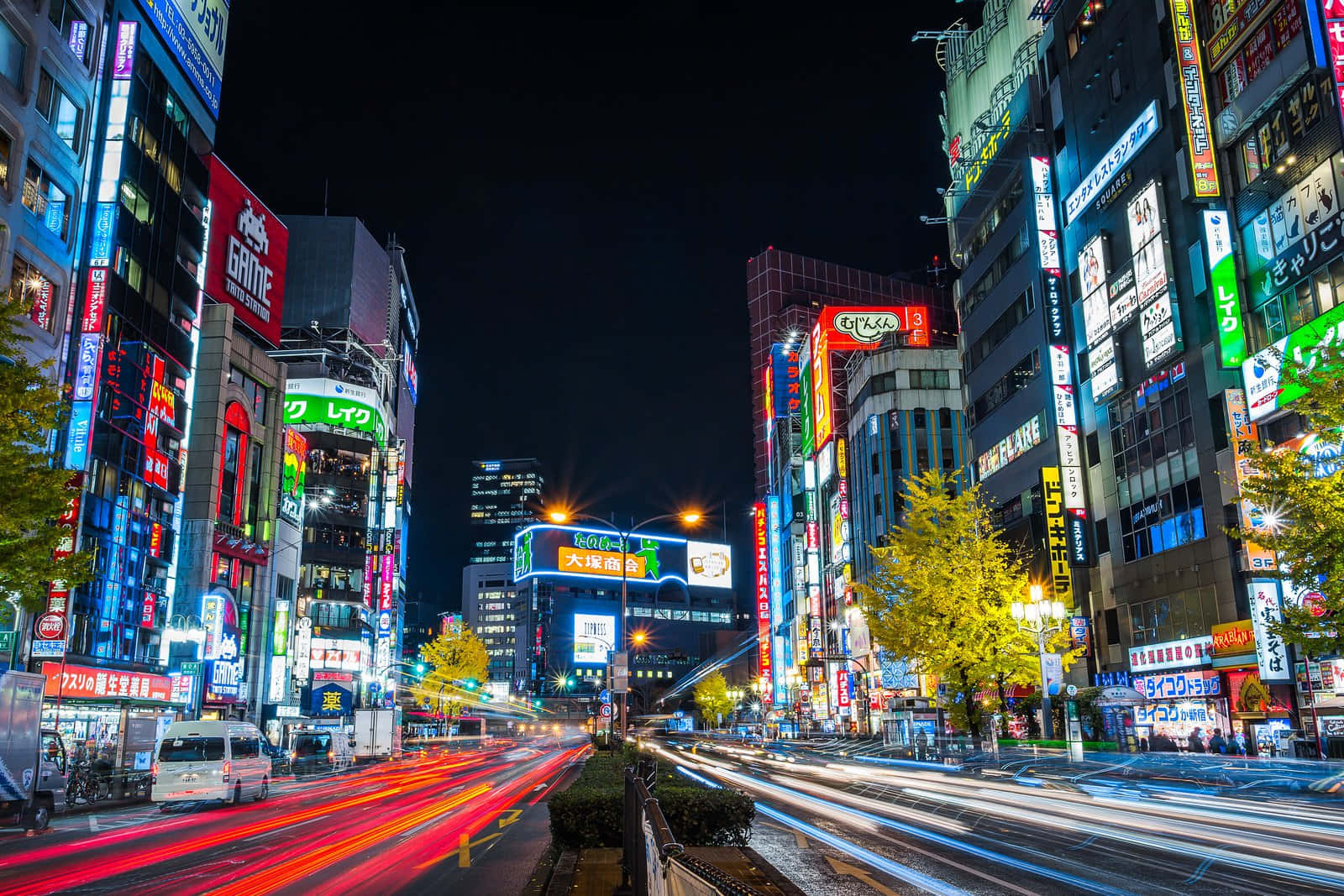 東京 桌布 壁紙 — 東京夜晚一條閃爍霓虹燈的街道，帶有交通的紅色和白色光條。
