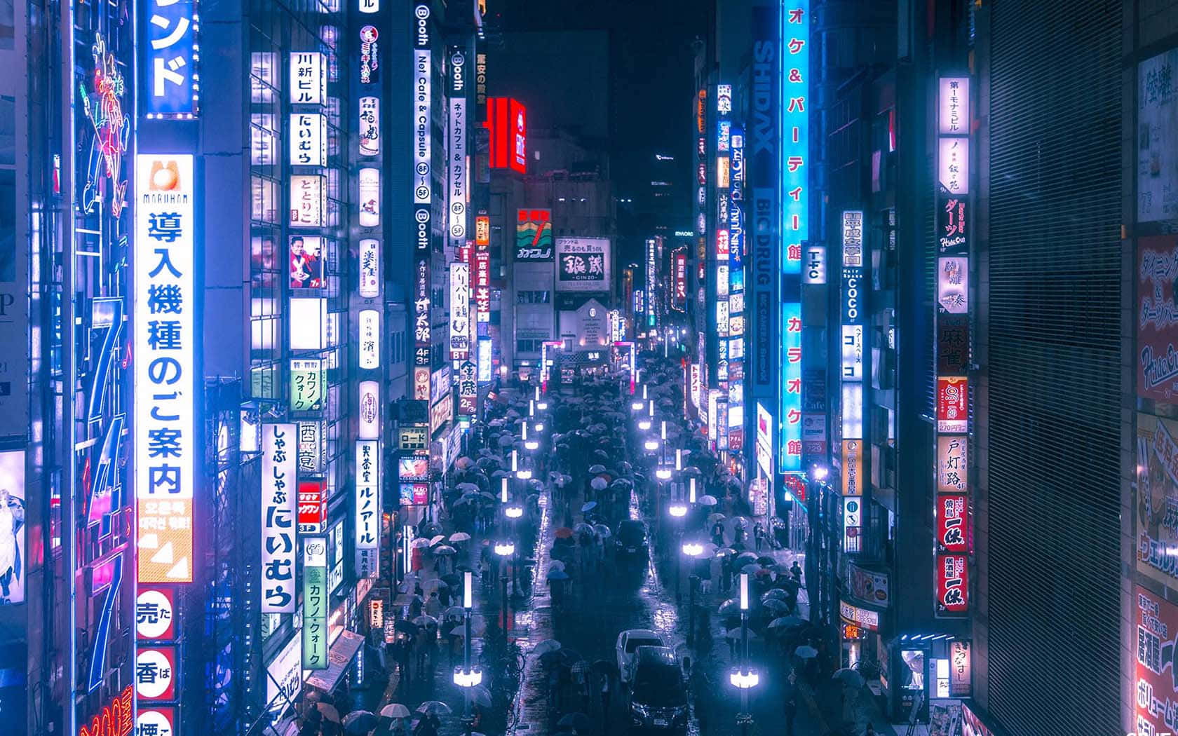 城市 桌布 壁紙 — 東京夜晚充滿霓虹燈光的街道，人群在發光招牌下穿梭，路面因雨水而濕滑。