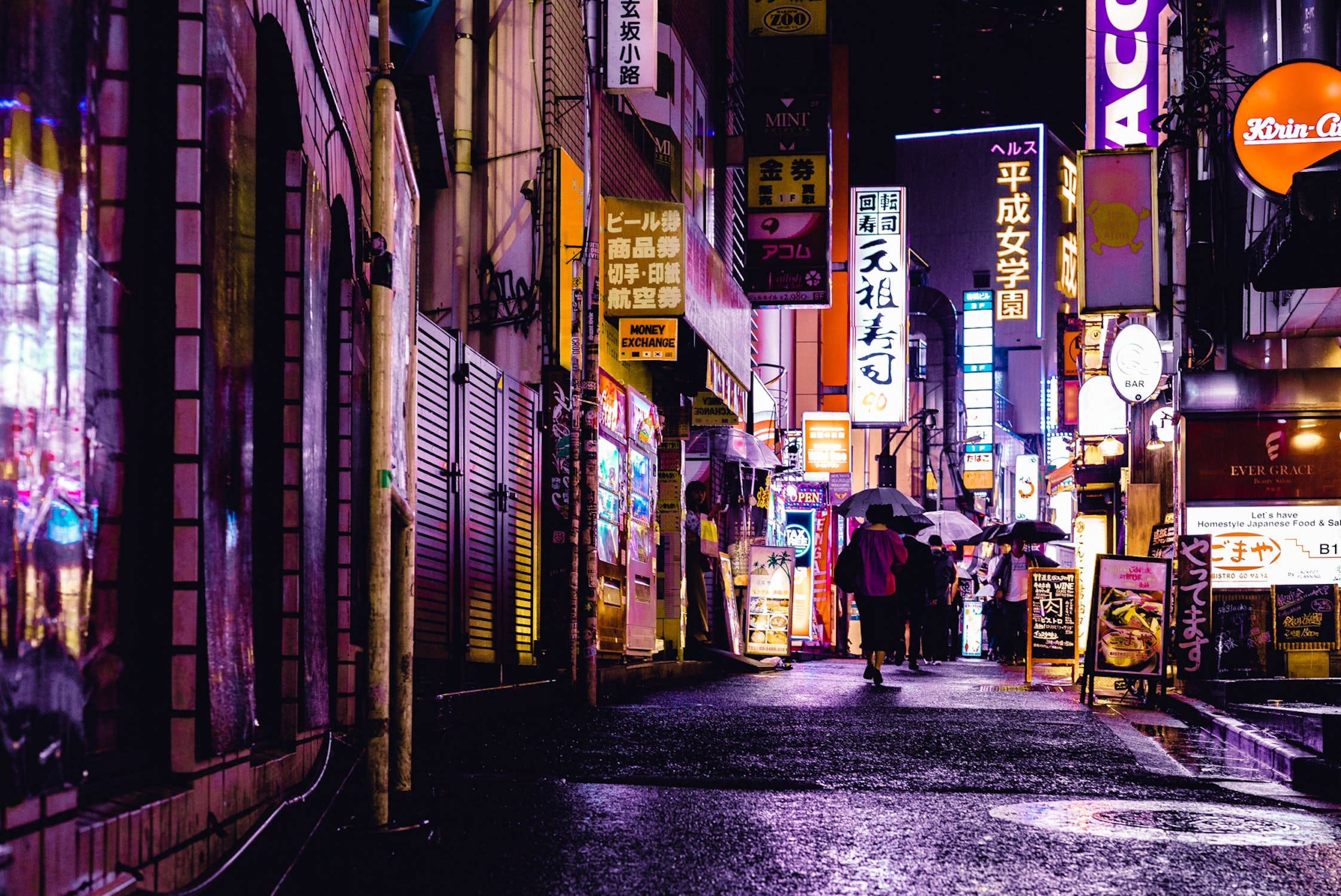 城市 桌布 壁紙 — 東京夜晚被雨淋濕的霓虹小巷，行人撐著傘在發光招牌下。