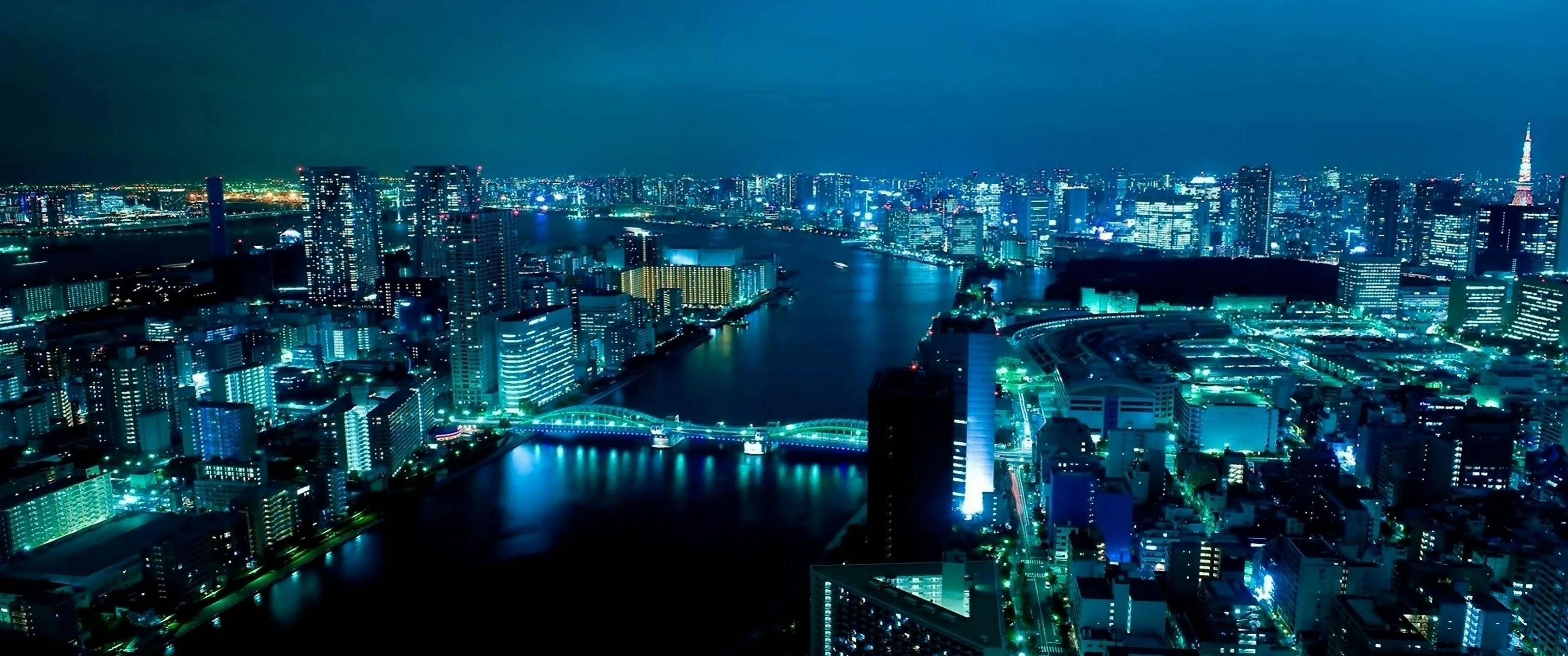 桌布 壁紙 — 東京夜景鳥瞰圖，摩天大樓閃爍，河流在黑暗天空下反射霓虹燈光。