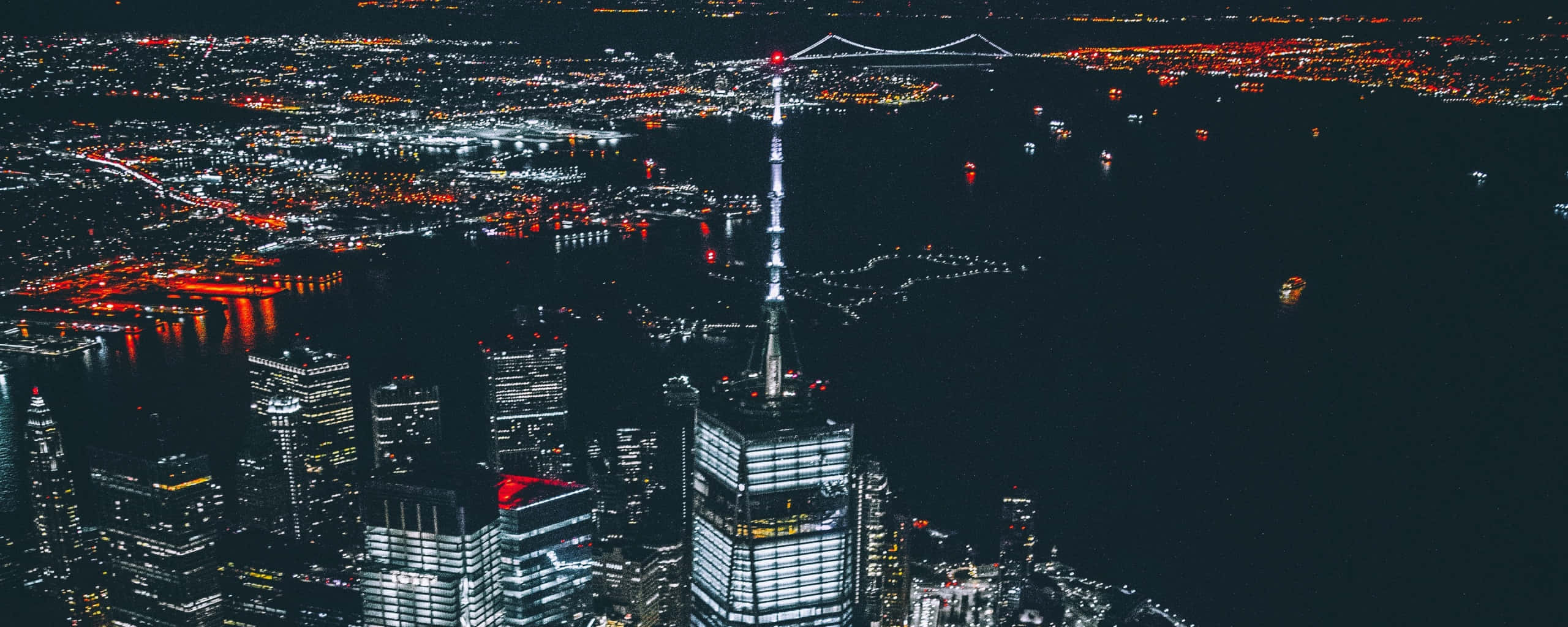 New York City 4K Ultra HD 桌布 壁紙 — 東京天際線的夜間空中景觀，照亮摩天大樓和橋樑，倒映在黑暗的水面上。