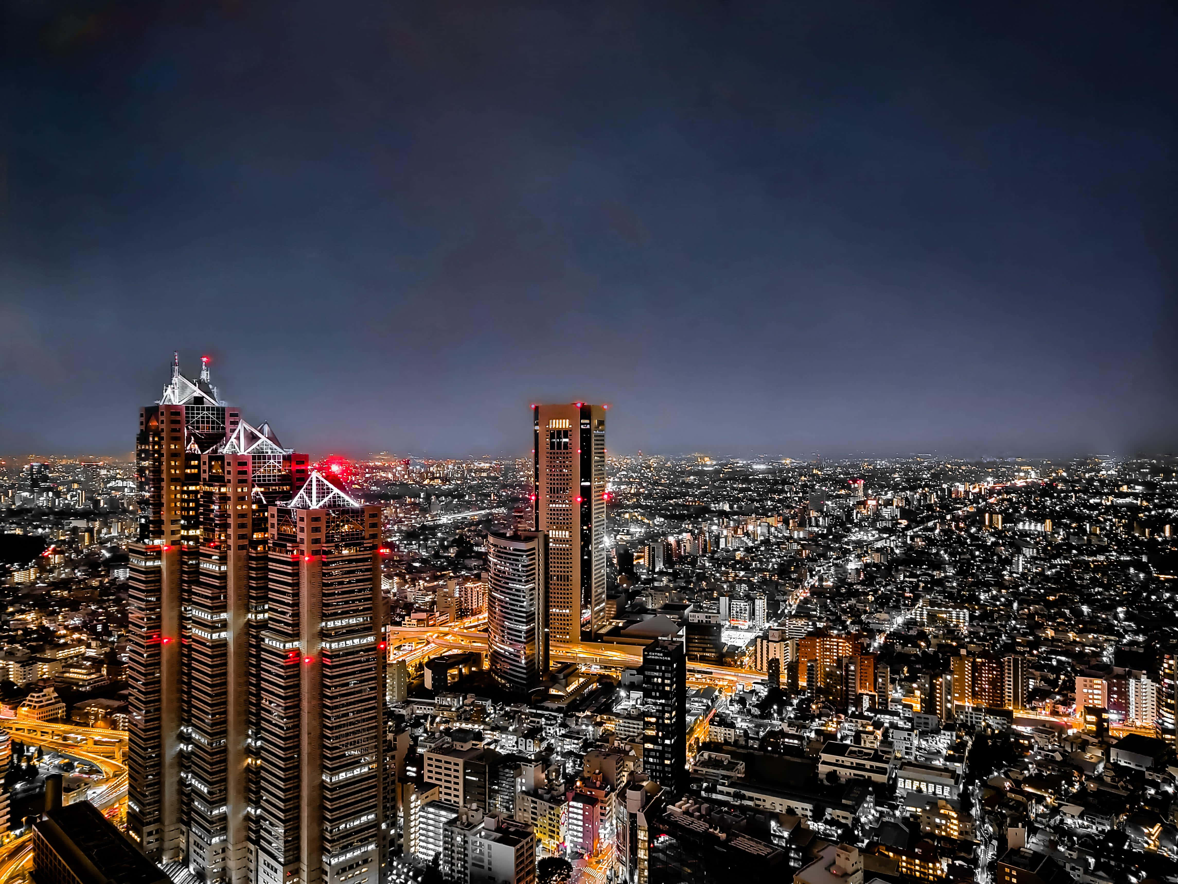Building 桌布 壁紙 — 東京璀璨天際線的夜間航拍圖，高聳的摩天大樓與廣闊的城市燈光在黑暗天空下閃耀。