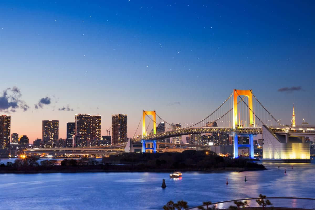 Rainbow Bridge 桌布 壁紙 — 東京的彩虹橋在水面上閃爍著鮮豔的光芒，映襯著繁星點點的暮色天空。