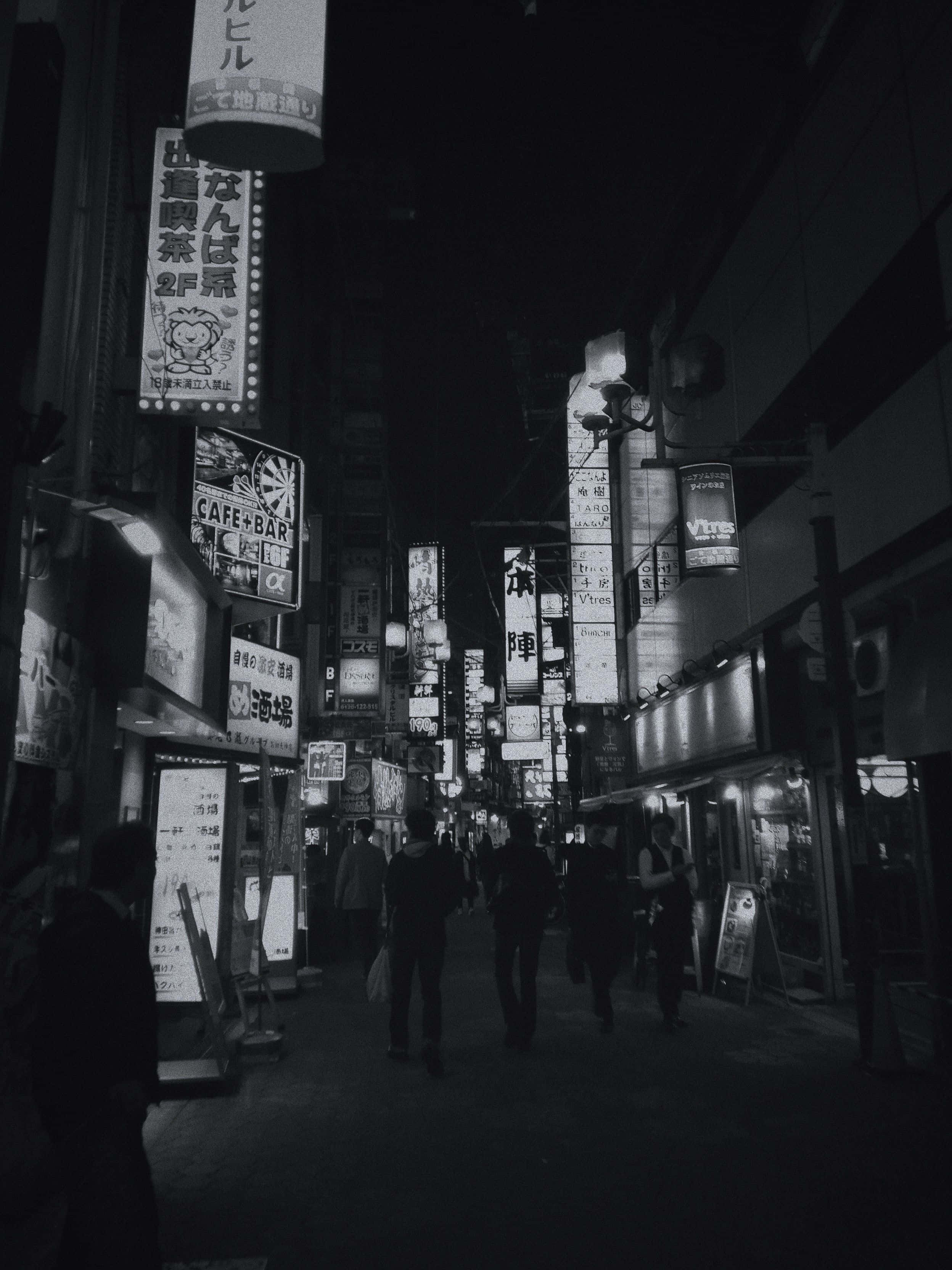 日本黑白 桌布 壁紙 — 東京繁華小巷的黑白夜景，霓虹招牌閃爍，行人剪影清晰可見。