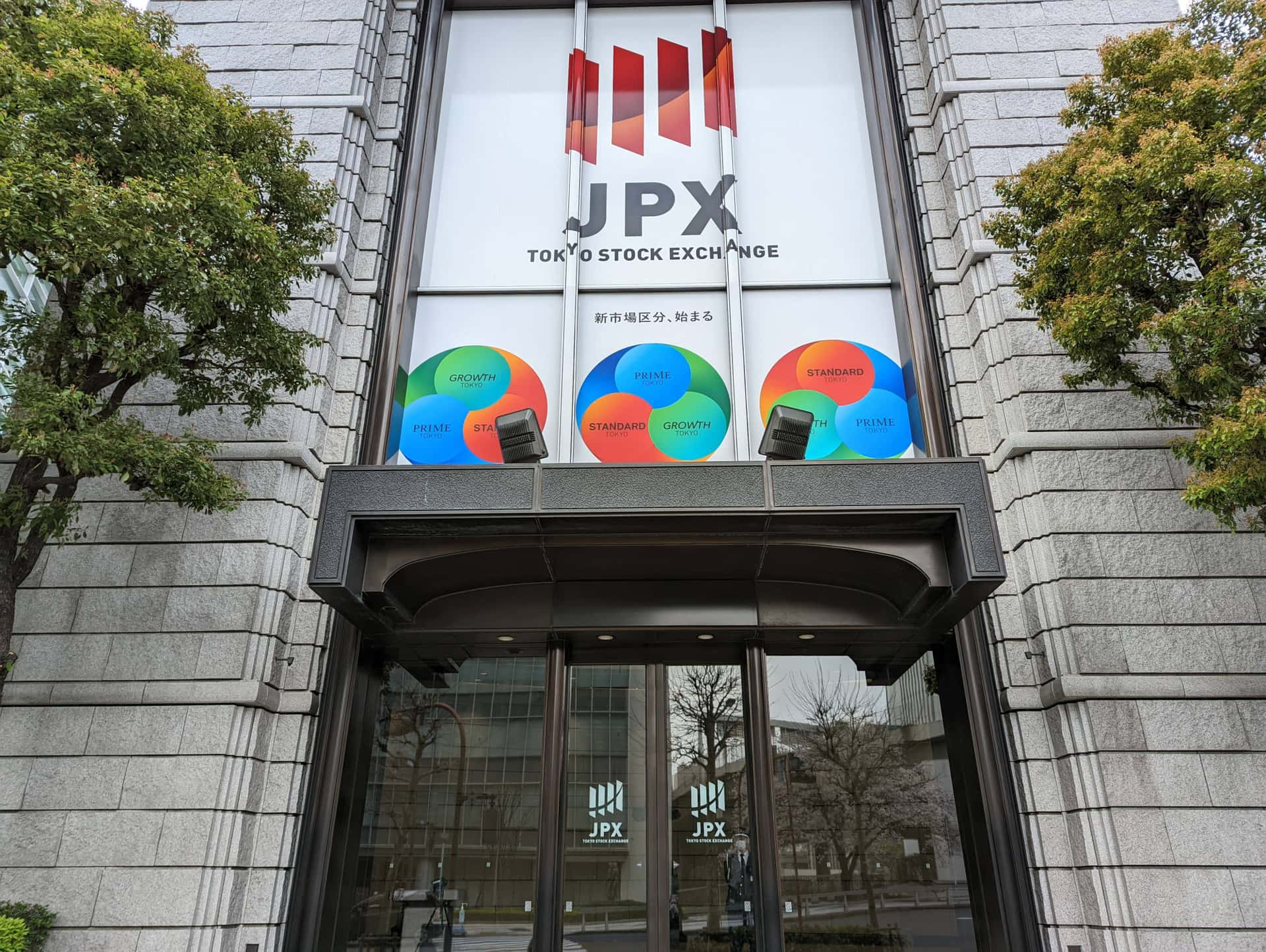 東京證券交易所大樓入口，帶有市場細分標誌和樹木 — 股市 壁紙