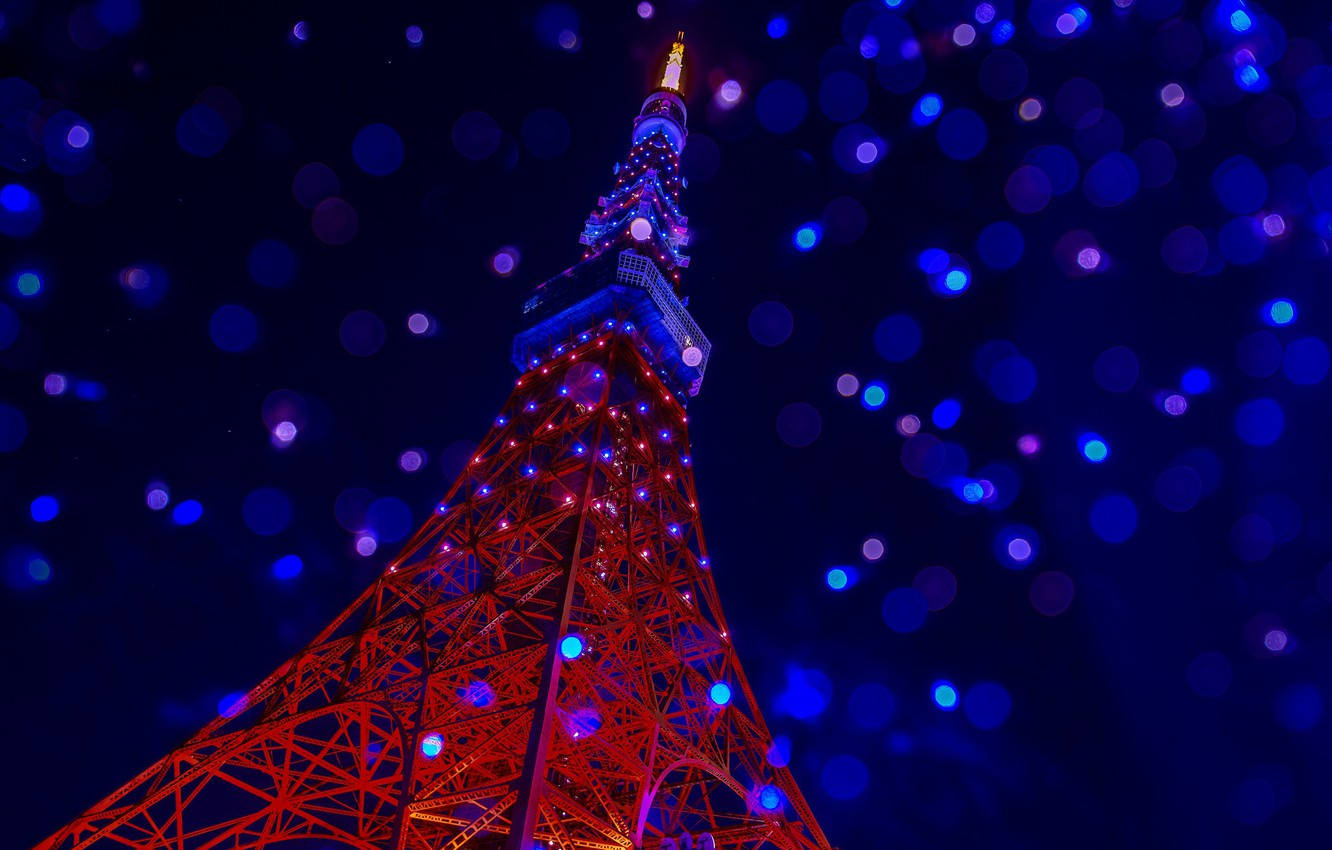 日本 桌布 壁紙 — 東京鐵塔在充滿閃爍散景燈光的黑暗天空襯托下，發出紅色和藍色的光芒。