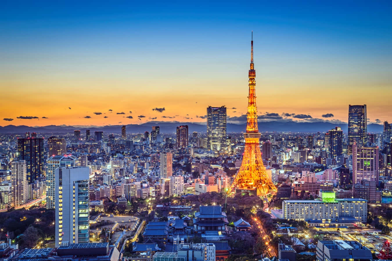 東京 桌布 壁紙 — 東京鐵塔在暮色天空下閃耀金光，城市燈光照亮下方廣闊的大都會。