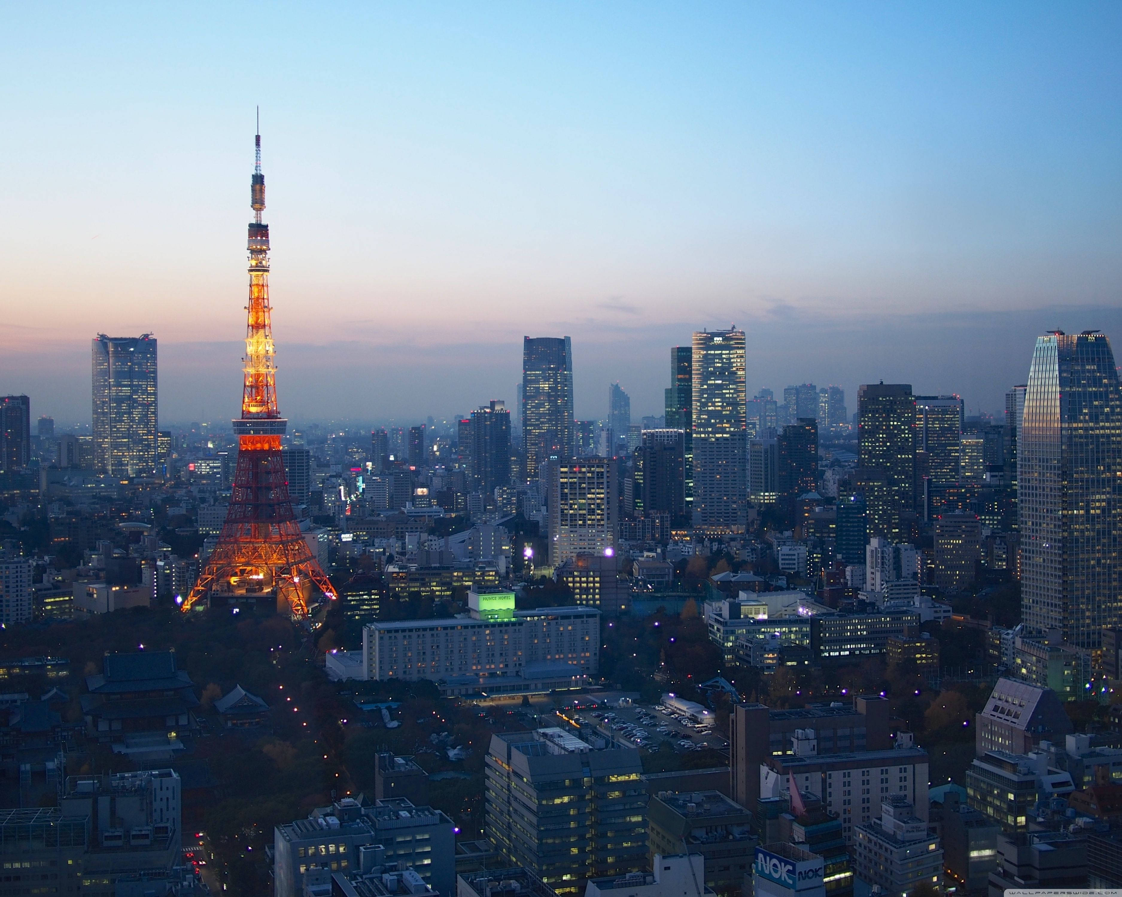 東京 桌布 壁紙 — 東京鐵塔在暮色天空中溫暖地發光，城市燈光在城市天際線上閃爍。