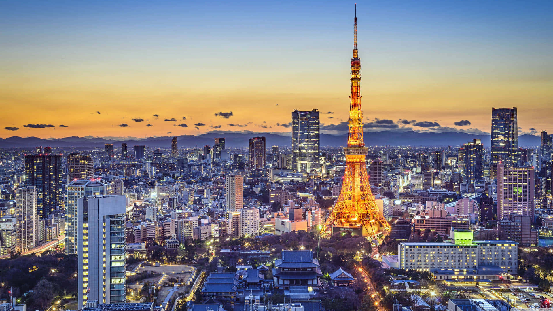 Harajuku 桌布 壁紙 — 東京鐵塔在暮色天空中閃耀金光，城市燈光照亮下方廣闊的大都會。