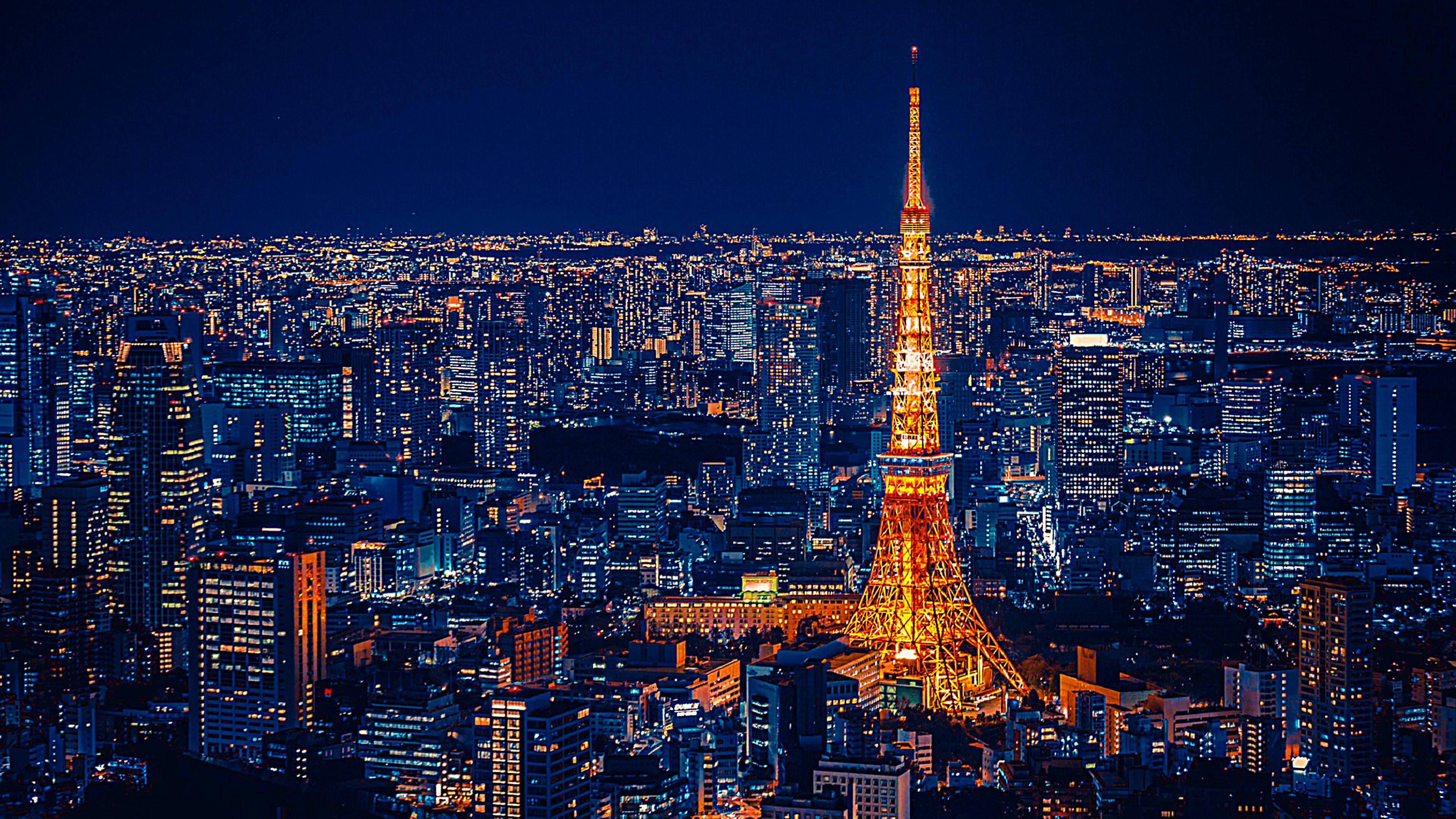 東京 桌布 壁紙 — 東京鐵塔在深藍色的夜空下溫暖地發光，俯瞰著閃爍燈光的廣闊城市景觀。