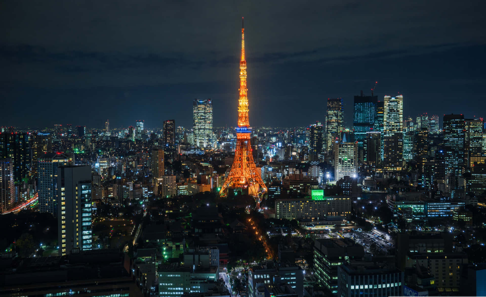 城市 桌布 壁紙 — 東京鐵塔在漆黑的天空中散發溫暖的光芒，城市的燈光照亮了下方廣闊的城市景觀。