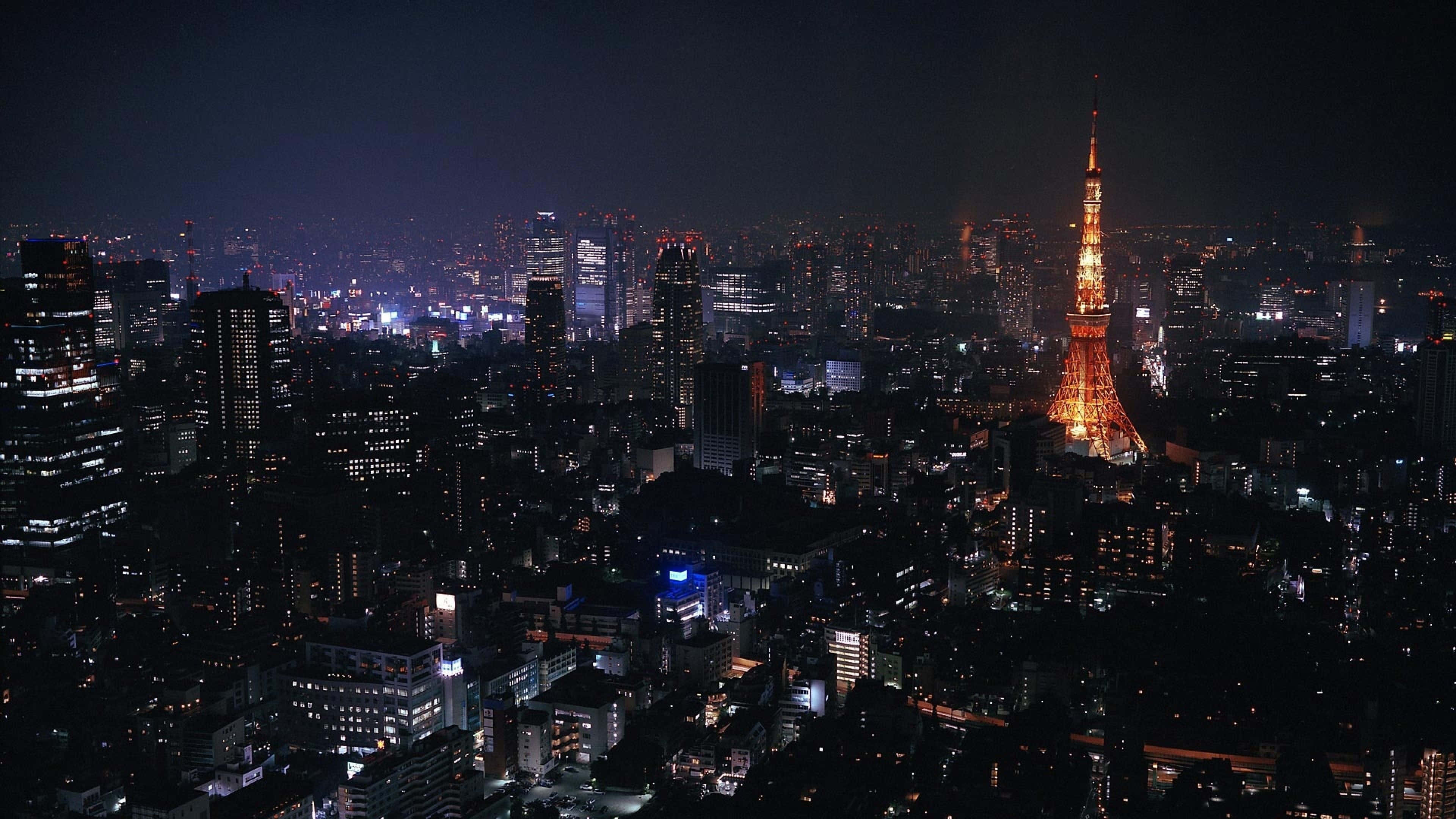 風景 桌布 壁紙 — 東京鐵塔在黑暗的天空中溫暖地發光，城市的燈光照亮了下方廣闊的城市景觀。