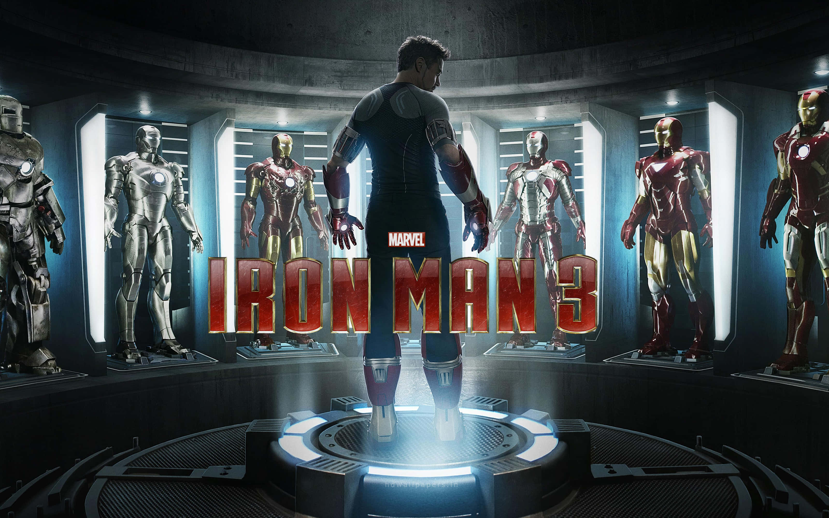 Superhero Movies 桌布 壁紙 — 東尼·史塔克站在高科技實驗室中，周圍環繞著發光的鋼鐵人戰衣，電影標題顯眼地展示。