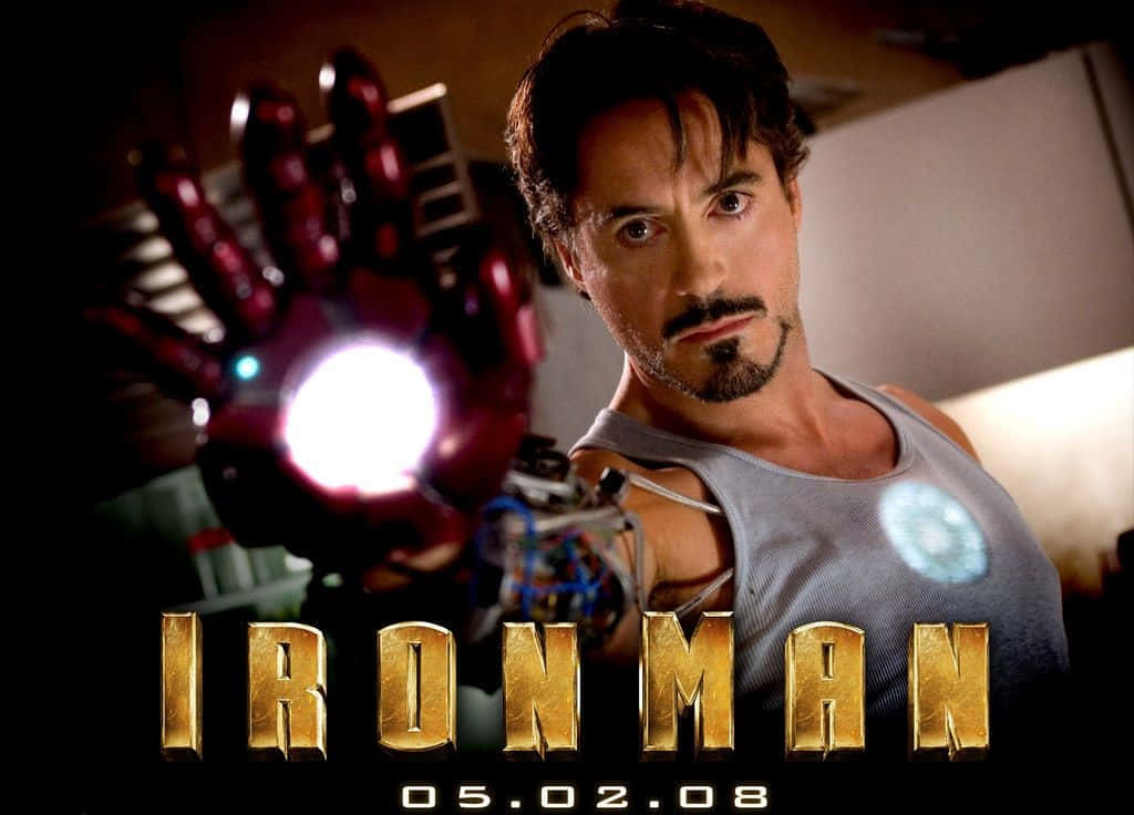 Iron Man Movies 桌布 壁紙 — 東尼·史塔克身穿灰色背心，在昏暗的實驗室中舉起發光的紅色斥力手套，眼神專注。