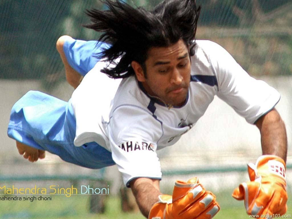 Ms Dhoni 桌布 壁紙 — 板球運動員 Mahendra Singh Dhoni 動態潛水，戴橙色手套和藍色短褲。