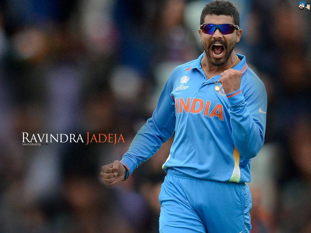Bokeh 桌布 壁紙 — 板球運動員 Ravindra Jadeja 身穿藍色印度球衣，戴著太陽眼鏡，張開嘴巴，握拳慶祝。