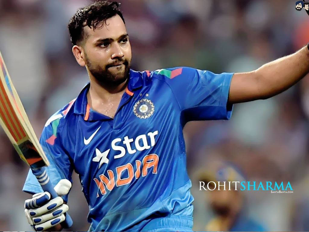 Rohit Sharma 桌布 壁紙 — 板球運動員 Rohit Sharma 身穿藍色印度球衣，在體育場燈光下的比賽中舉起球棒慶祝。