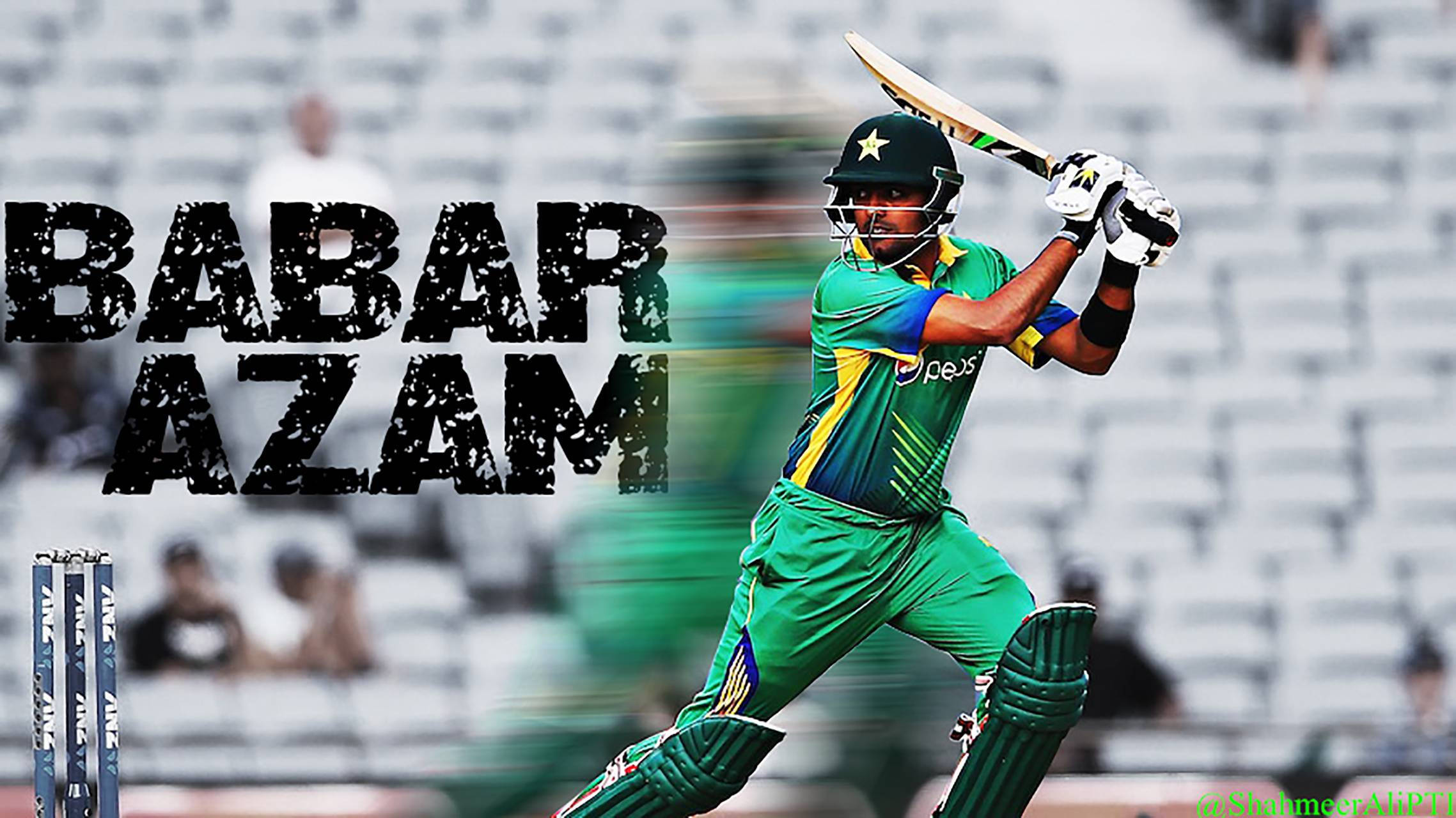 Babar 桌布 壁紙 — 板球運動員Babar Azam身穿綠色制服，在模糊的體育場背景下揮動球拍的中間動作。