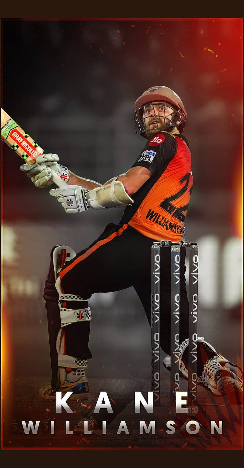 Sunrisers Hyderabad 桌布 壁紙 — 板球運動員Kane Williamson身穿橙色和黑色制服，在揮棒中，身後有三柱門，背景是火紅色的。