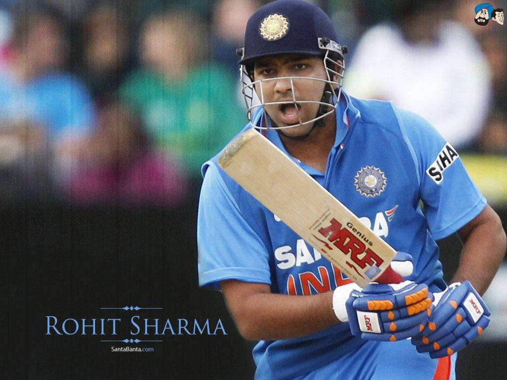 Rohit Sharma 桌布 壁紙 — 板球運動員羅希特·夏爾馬身穿藍色印度球衣，在比賽中揮棒中段，神情專注。