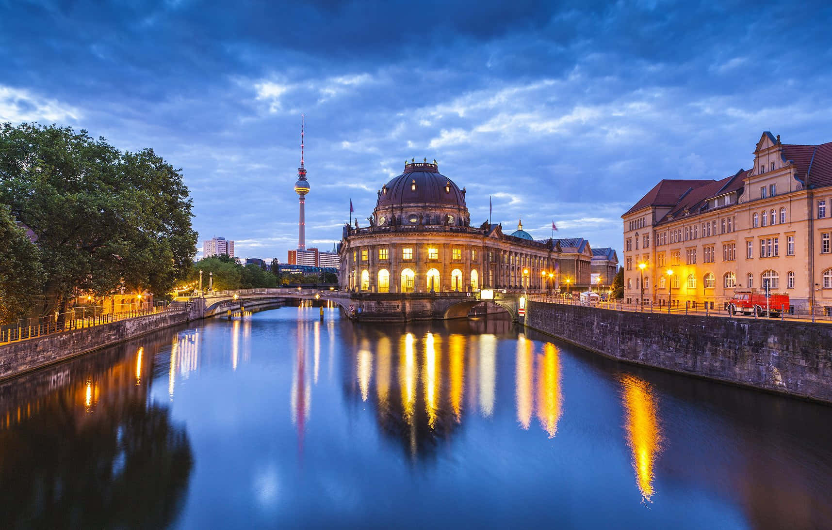 Berlin 桌布 壁紙 — 柏林國會大廈和電視塔在暮色中溫暖地發光，它們的倒影在下方平靜的河流中閃爍。