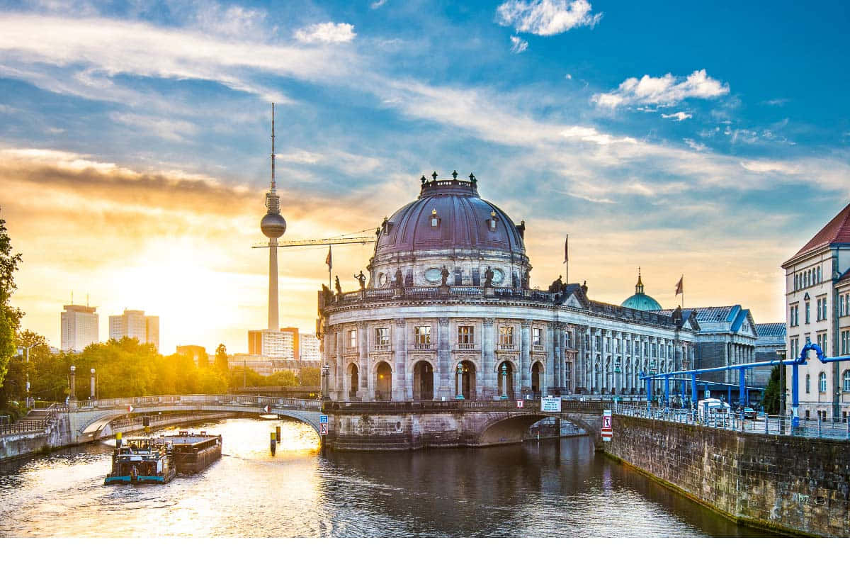 Berlin 桌布 壁紙 — 柏林國會大廈在日落時發光，背景有電視塔，河上有船。