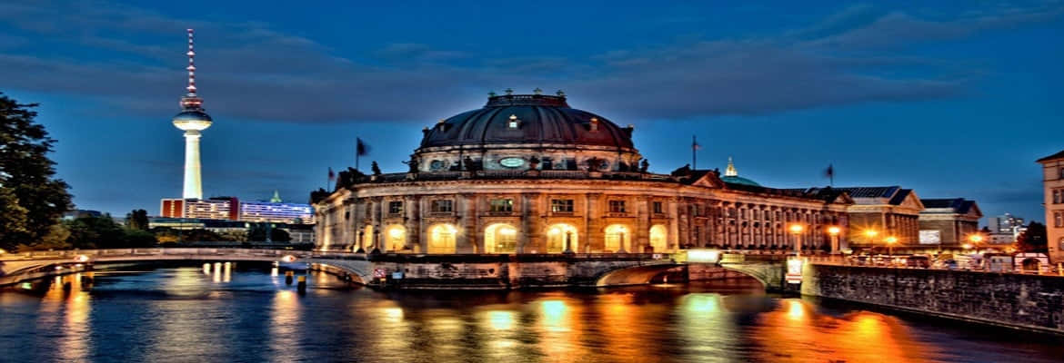 Berlin 桌布 壁紙 — 柏林國會大廈在黃昏時溫暖地發光，圓頂亮起，倒影在下方河流中閃爍。