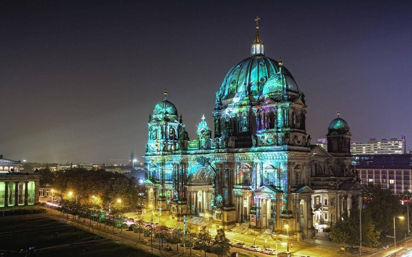 Berlin 桌布 壁紙 — 柏林大教堂在漆黑的夜空中被鮮豔的藍色和綠色燈光照亮，背景是城市燈光。