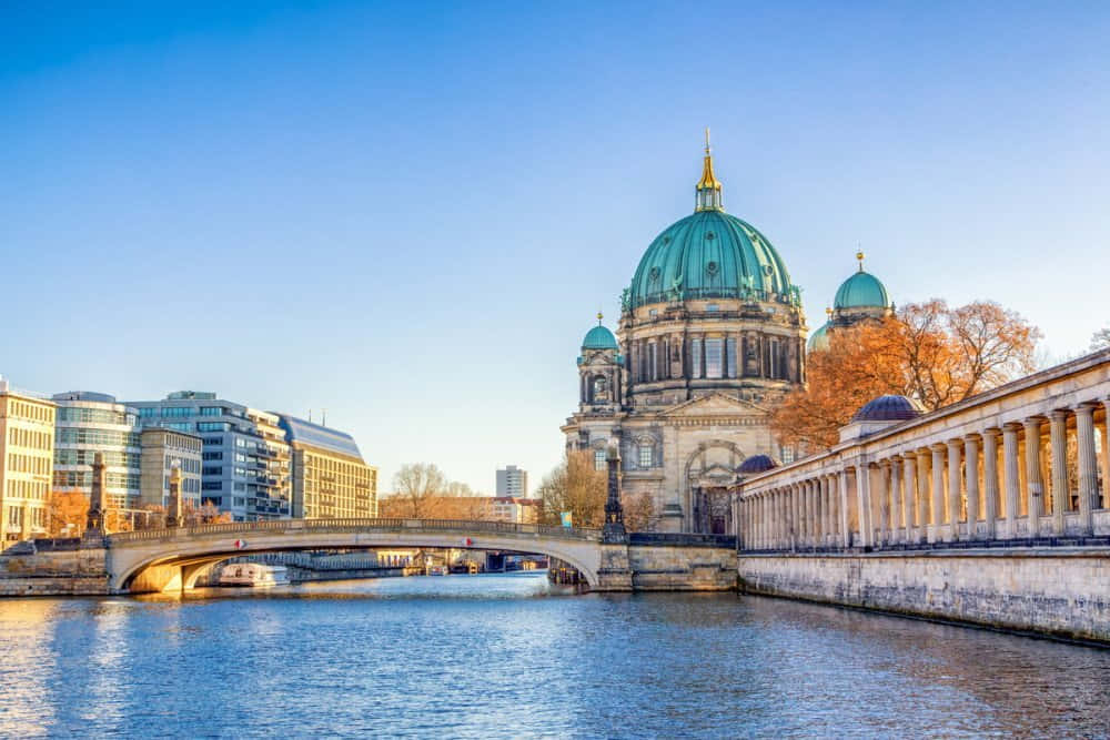 Berlin 桌布 壁紙 — 柏林大教堂擁有綠色圓頂，在秋樹襯托下，於清澈藍天下雄偉地矗立在河邊。
