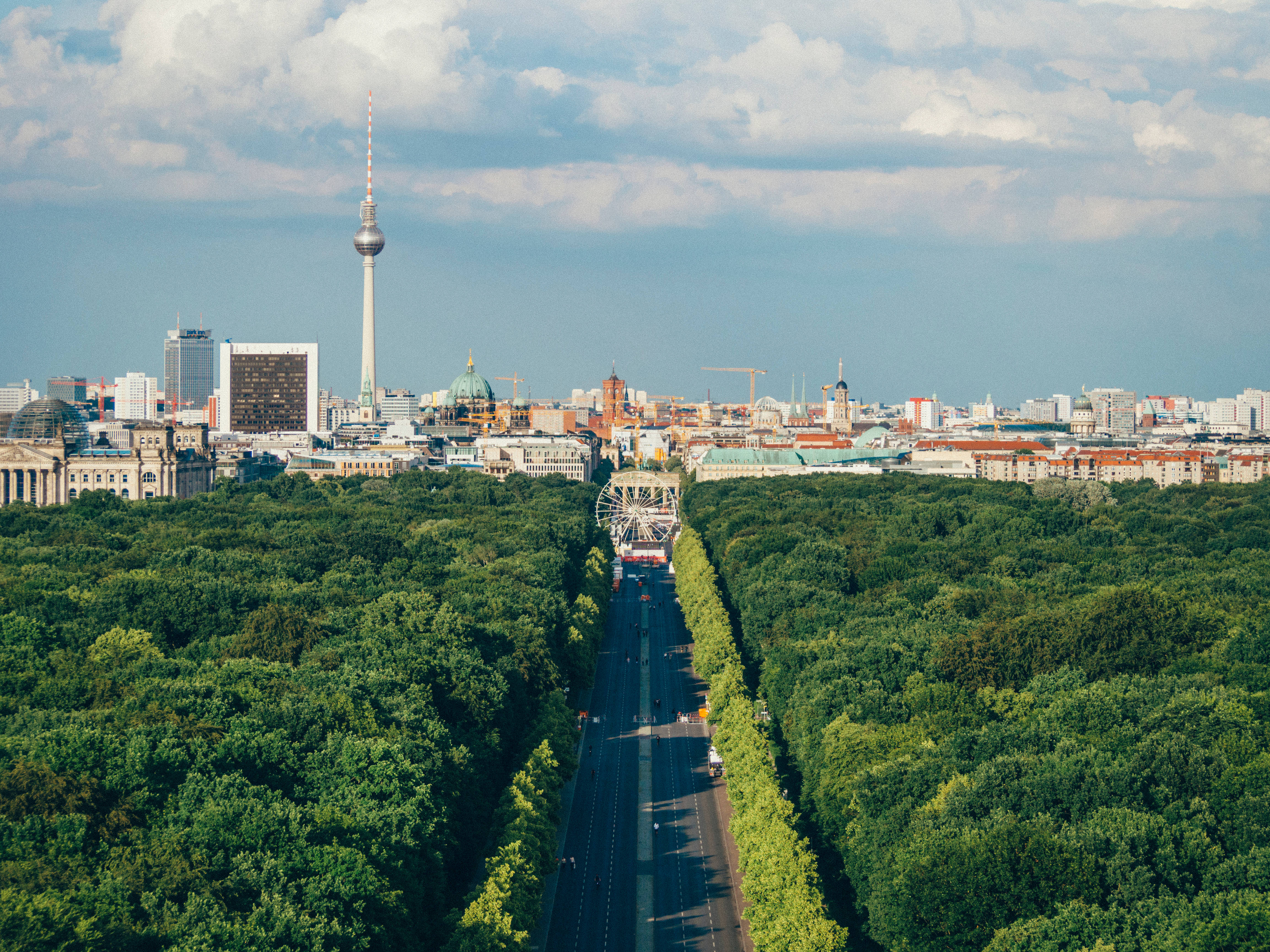 Berlin 桌布 壁紙 — 柏林天際線的鳥瞰圖，標誌性的電視塔聳立在茂密的綠色森林之上，森林兩旁是長長的林蔭大道。