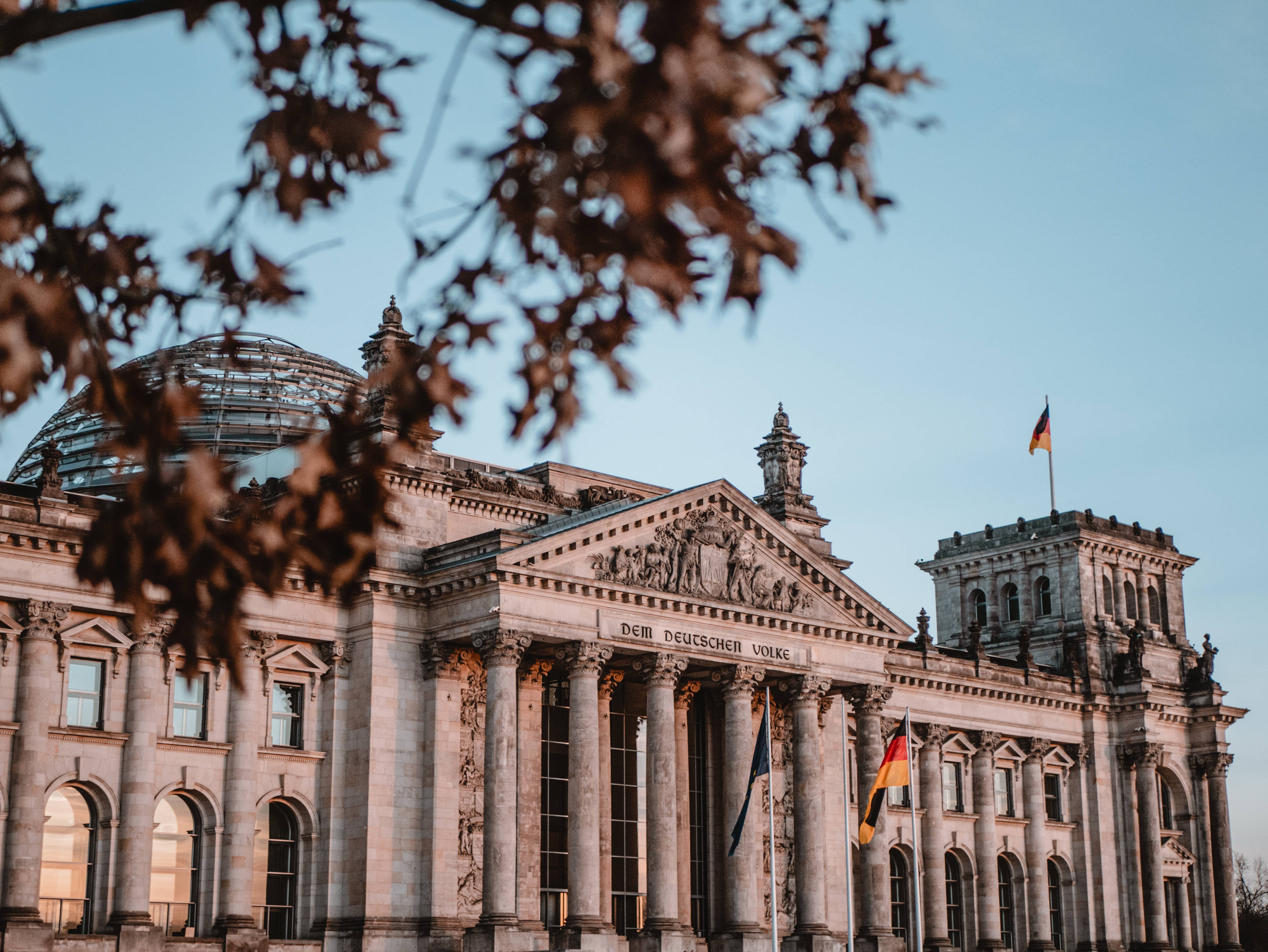 Berlin 桌布 壁紙 — 柏林宏偉的新古典主義國會大廈，被秋葉環繞，襯托著清澈的藍天。