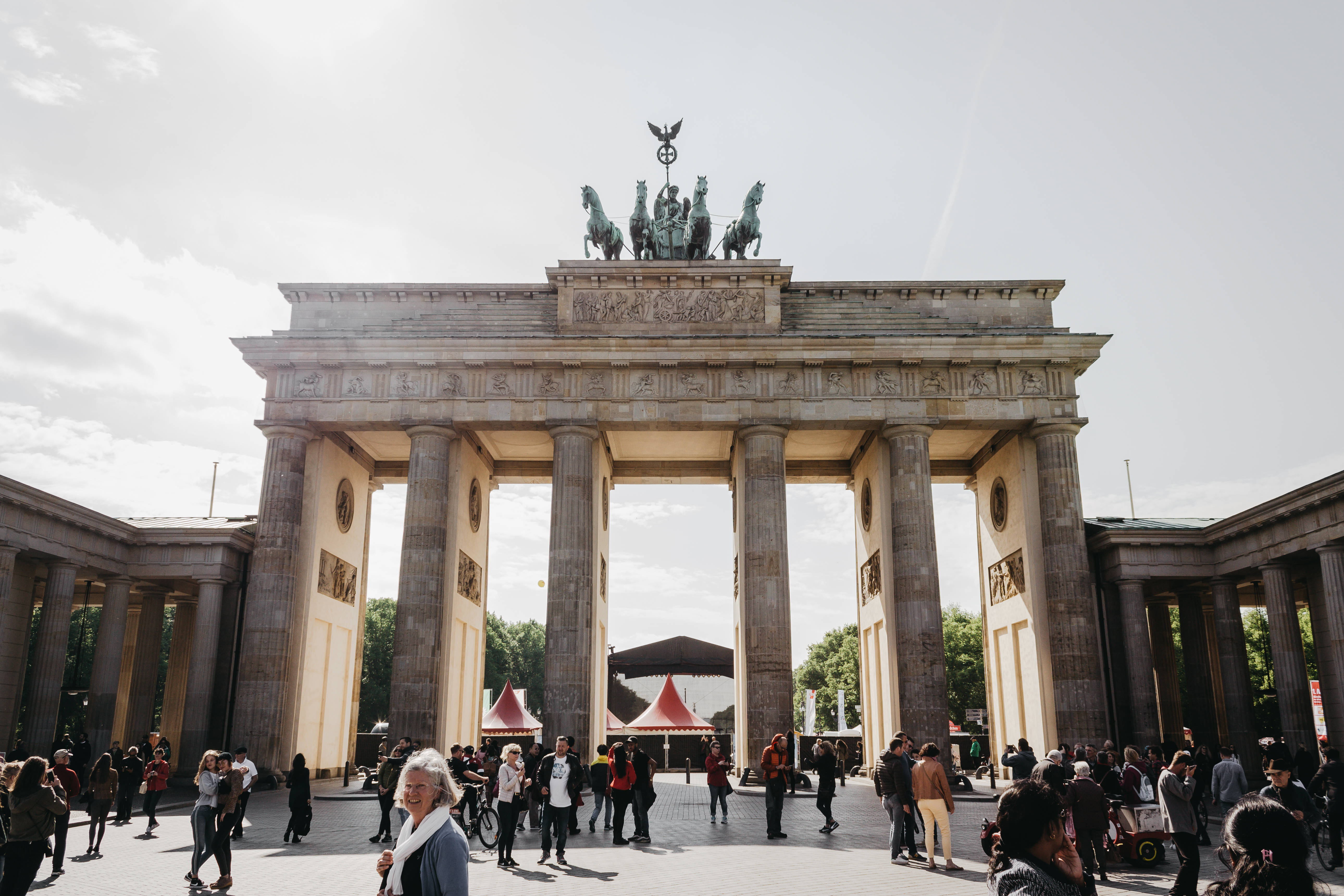 Berlin 桌布 壁紙 — 柏林布蘭登堡門在晴朗的天空下巍然聳立，遊客在其宏偉的新古典主義柱廊下行走。