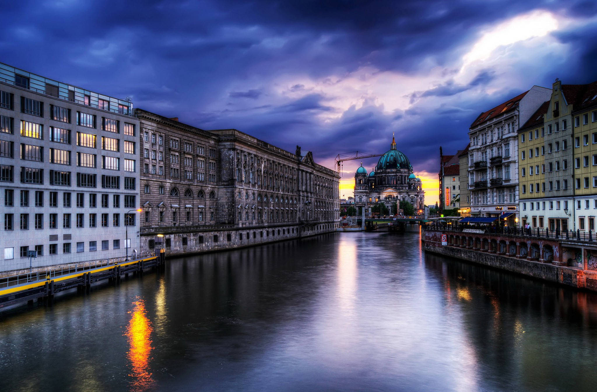 Berlin 桌布 壁紙 — 柏林施普雷河在暮色中的戲劇性景觀，兩旁是歷史建築和燈火通明的柏林大教堂圓頂，天空呈現憂鬱的紫色。