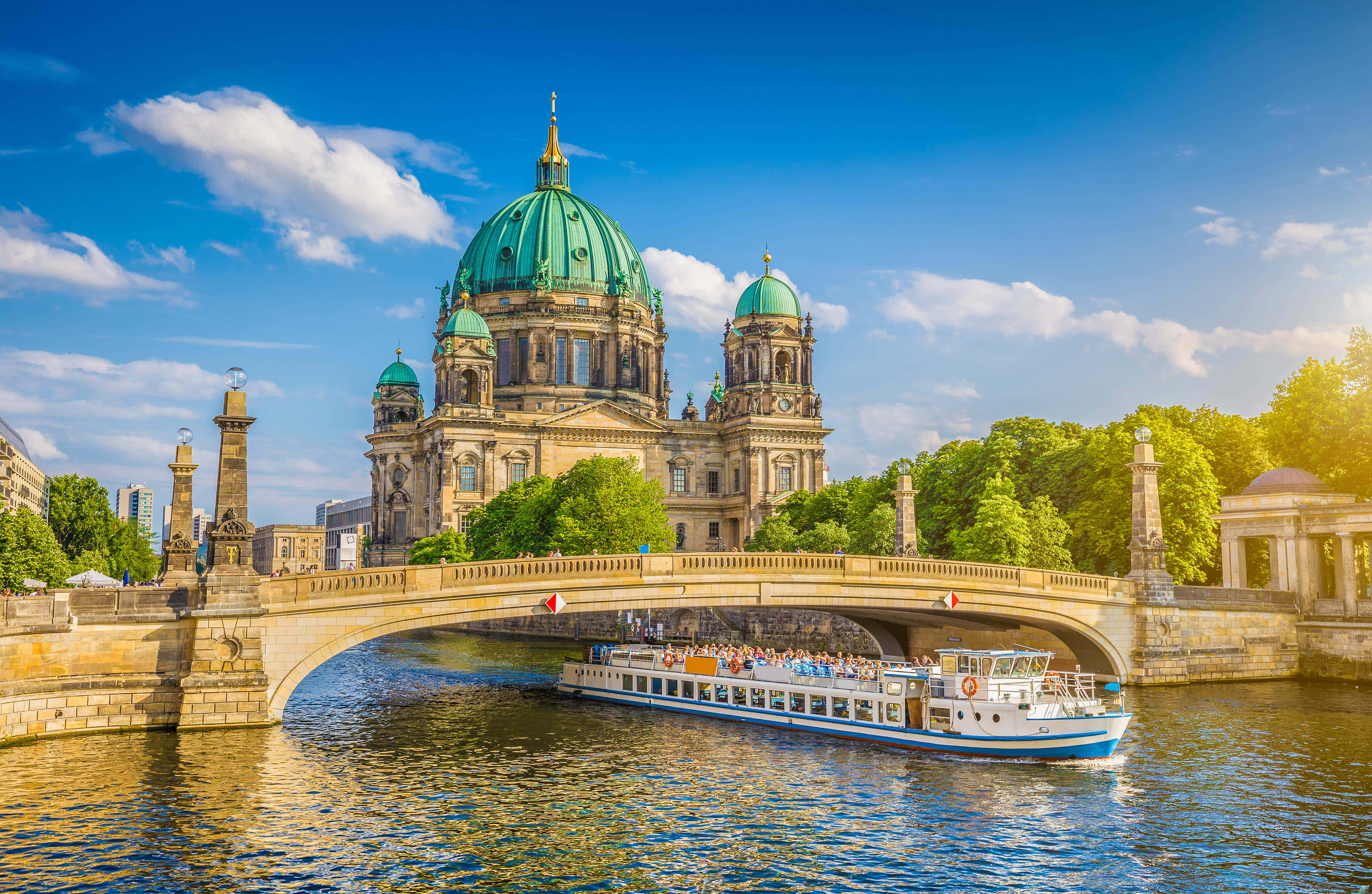 Berlin 桌布 壁紙 — 柏林陽光明媚的一天，一艘觀光船在石橋下穿過，靠近標誌性的柏林大教堂及其綠色圓頂。