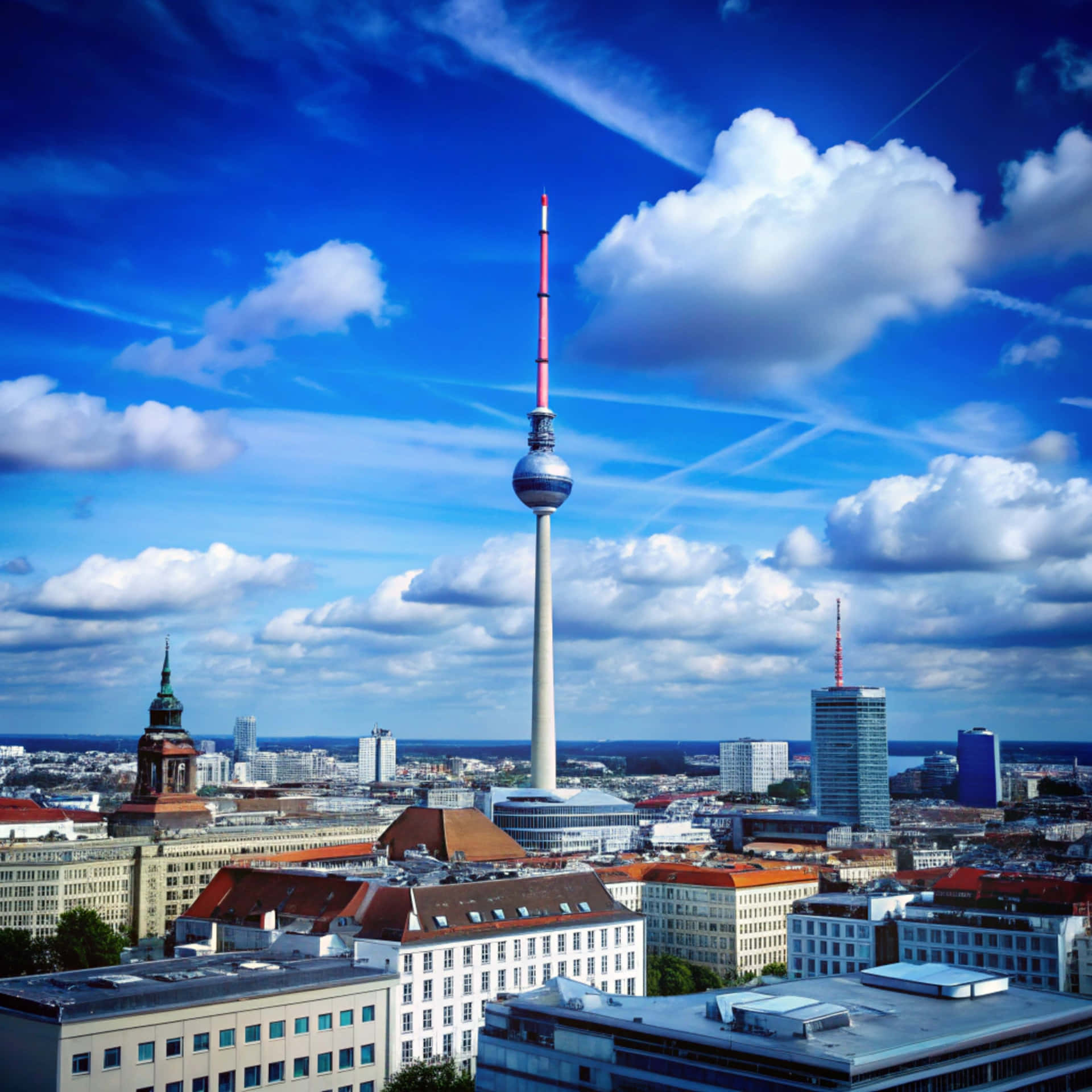 Berlin Skyline 壁紙 — 柏林電視塔在充滿活力的藍天下，伴隨著蓬鬆的白雲和遠處的水面，聳立於城市景觀之上。