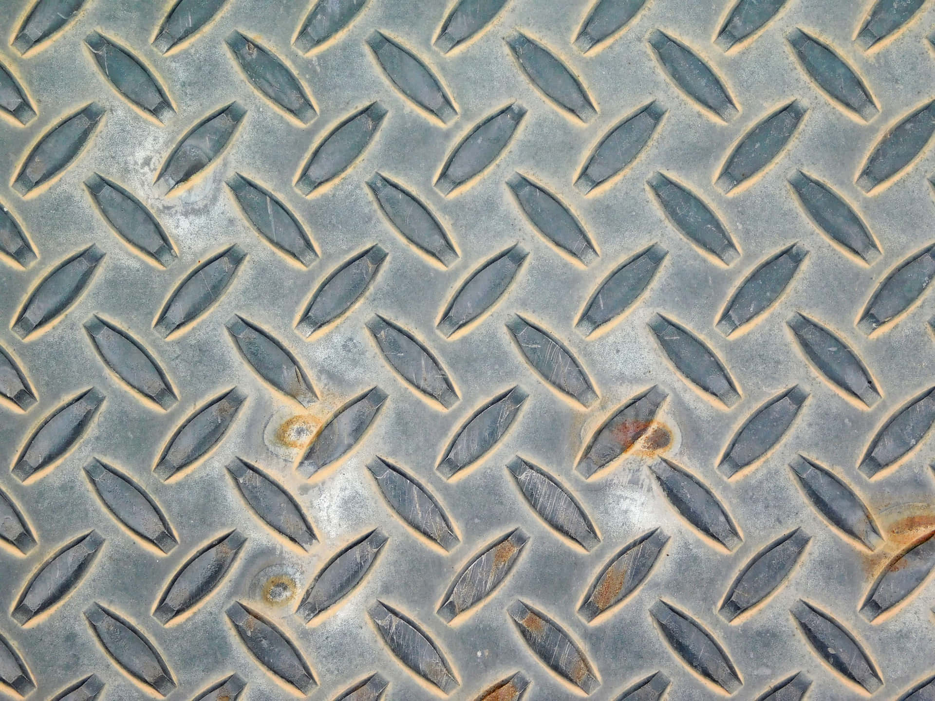 Metal texture 壁紙 — 柔光下風化菱形金屬板近距離特寫，帶有鏽斑和紋理脊線。