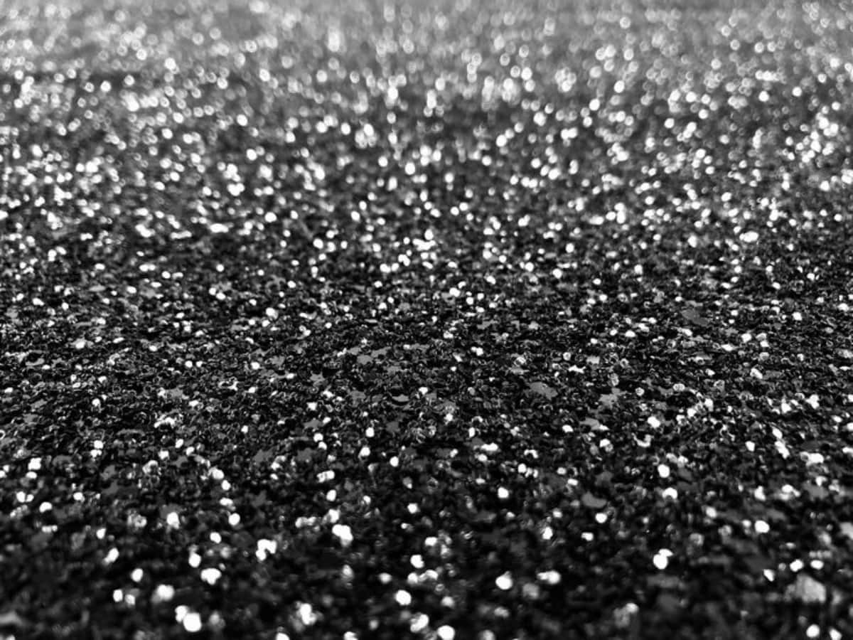 Black Glitter 桌布 壁紙 — 柔光下黑色亮粉紋理的近距離特寫，帶有閃爍的銀色亮點。