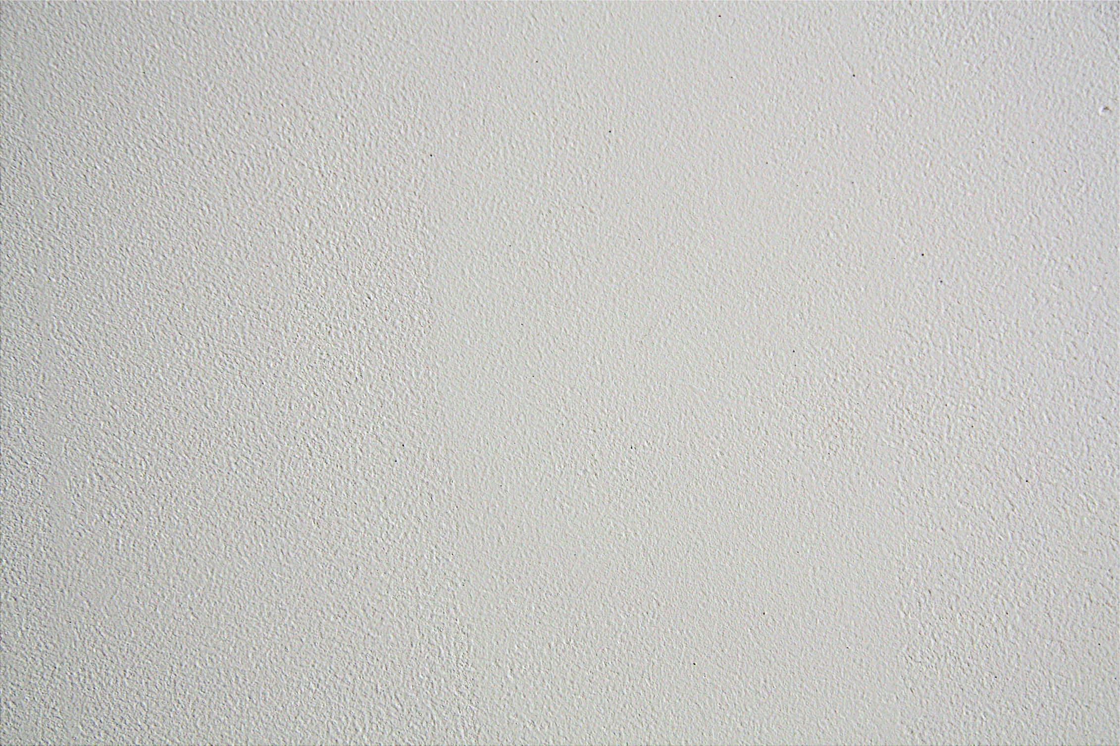 White Wall 桌布 壁紙 — 柔和光線下，光滑白色紋理牆壁的特寫，帶有細微顆粒和隱約斑點。