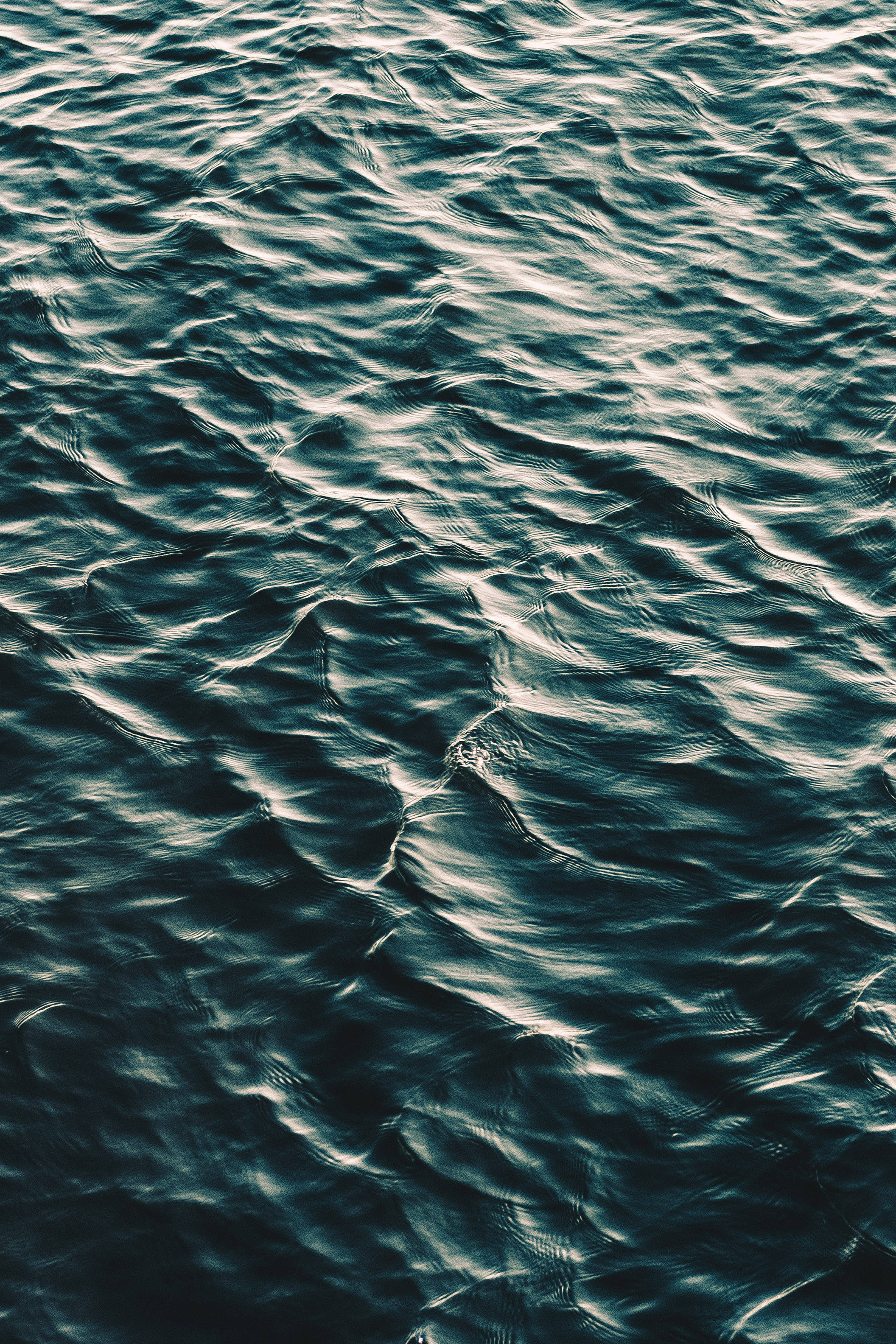 animated water 桌布 壁紙 — 柔和光線下深藍綠色和銀色亮點的紋理海浪特寫。