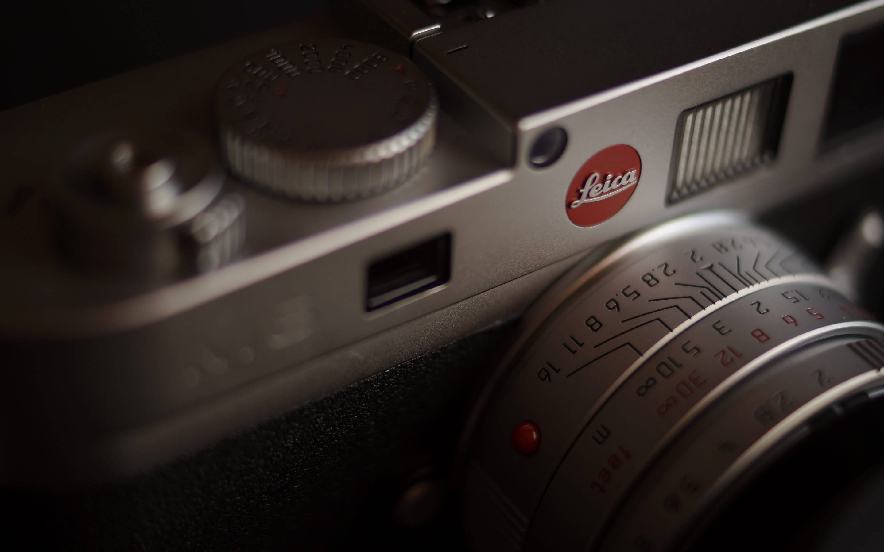 紅色動圖 桌布 壁紙 — 柔和光線下銀色 Leica 相機的特寫，帶有紅色標誌和詳細的鏡頭標記。