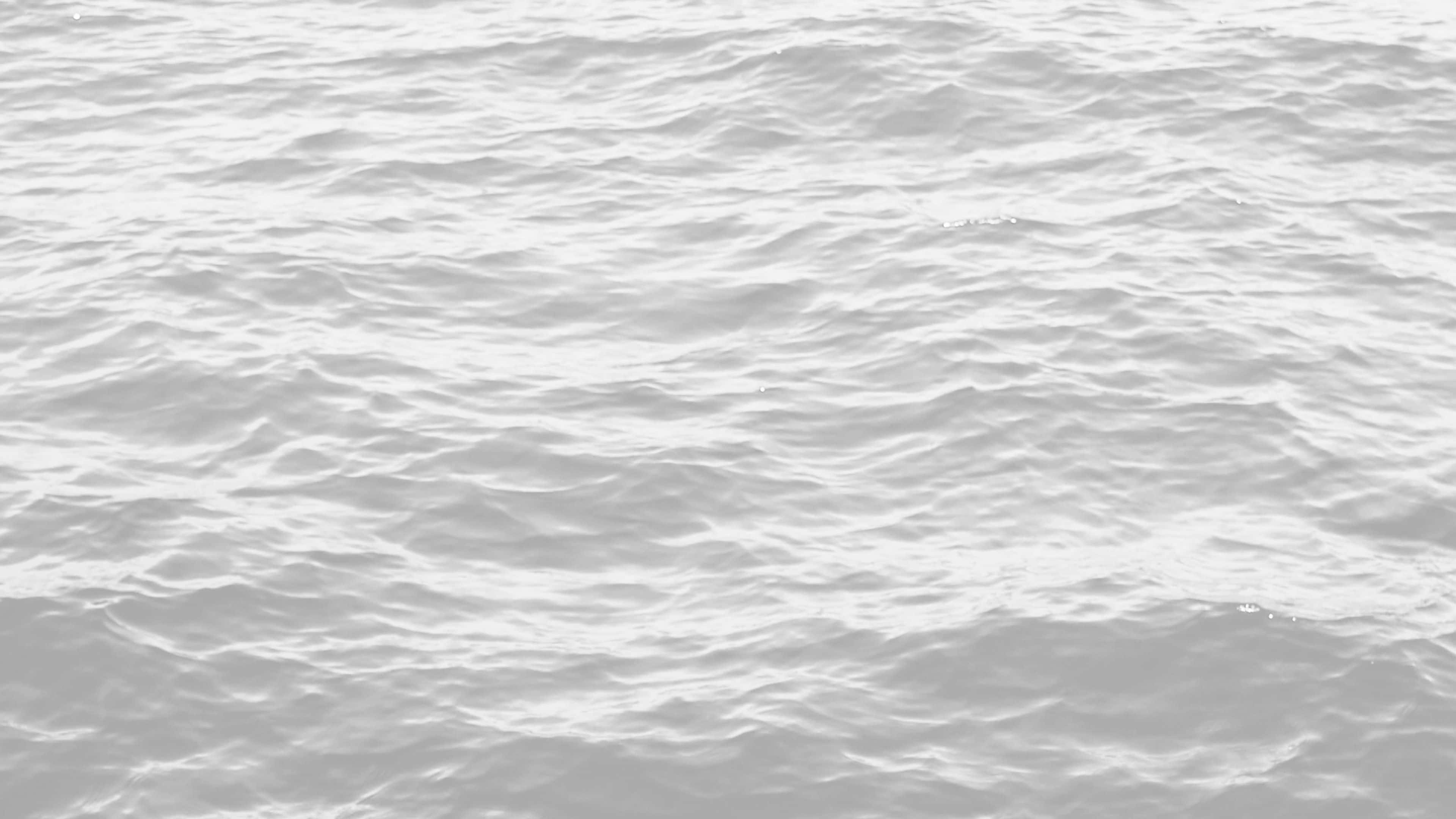 Black And White Ocean 桌布 壁紙 — 柔和光線在微細波浪上反射的單色水面近距離特寫。