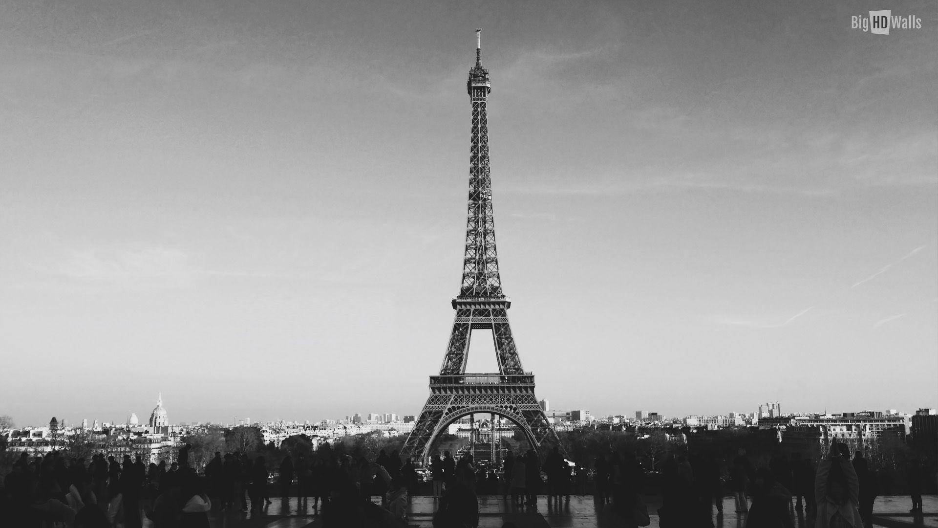 Eiffel Tower 桌布 壁紙 — 柔和天空下，巴黎上空高聳的艾菲爾鐵塔黑白景觀，塔底聚集人群。